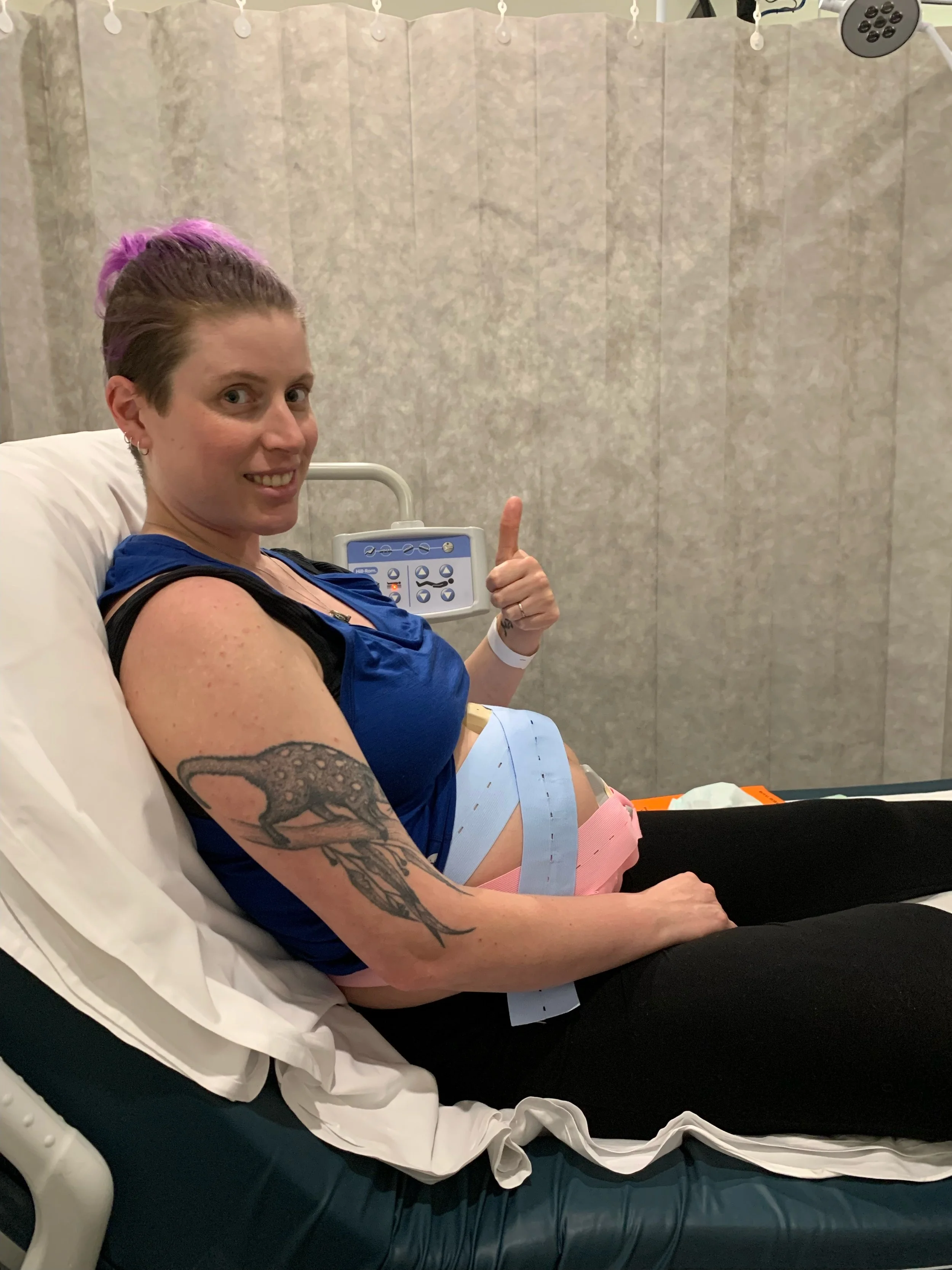 a person sitting up in a hospital bed with foetal monitoring on