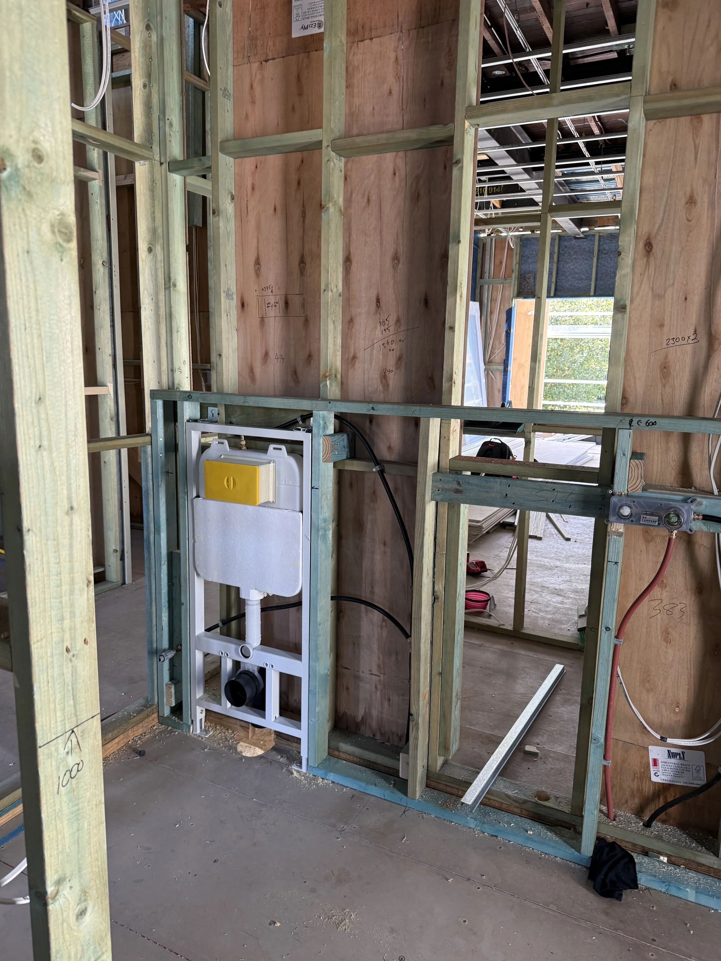 Construction site of a bathroom with wooden framing and plumbing for a toilet installation.