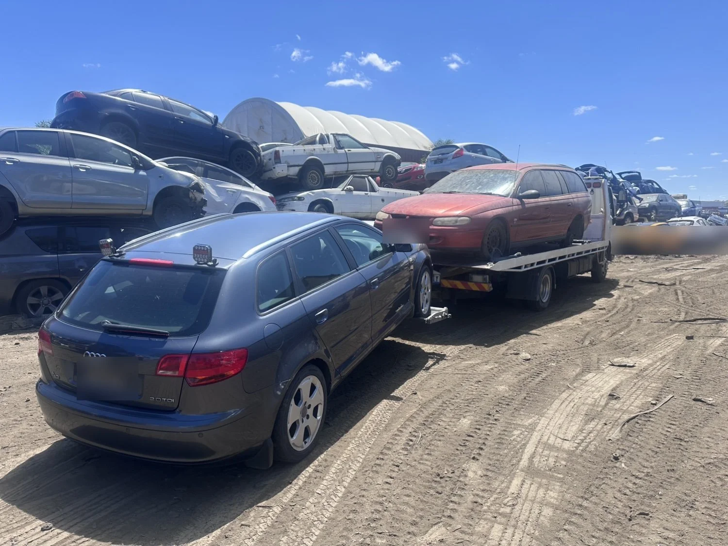 A faded red Holden Commodore wagon on our tilt tray, with a grey Audi hatchback parked behind it