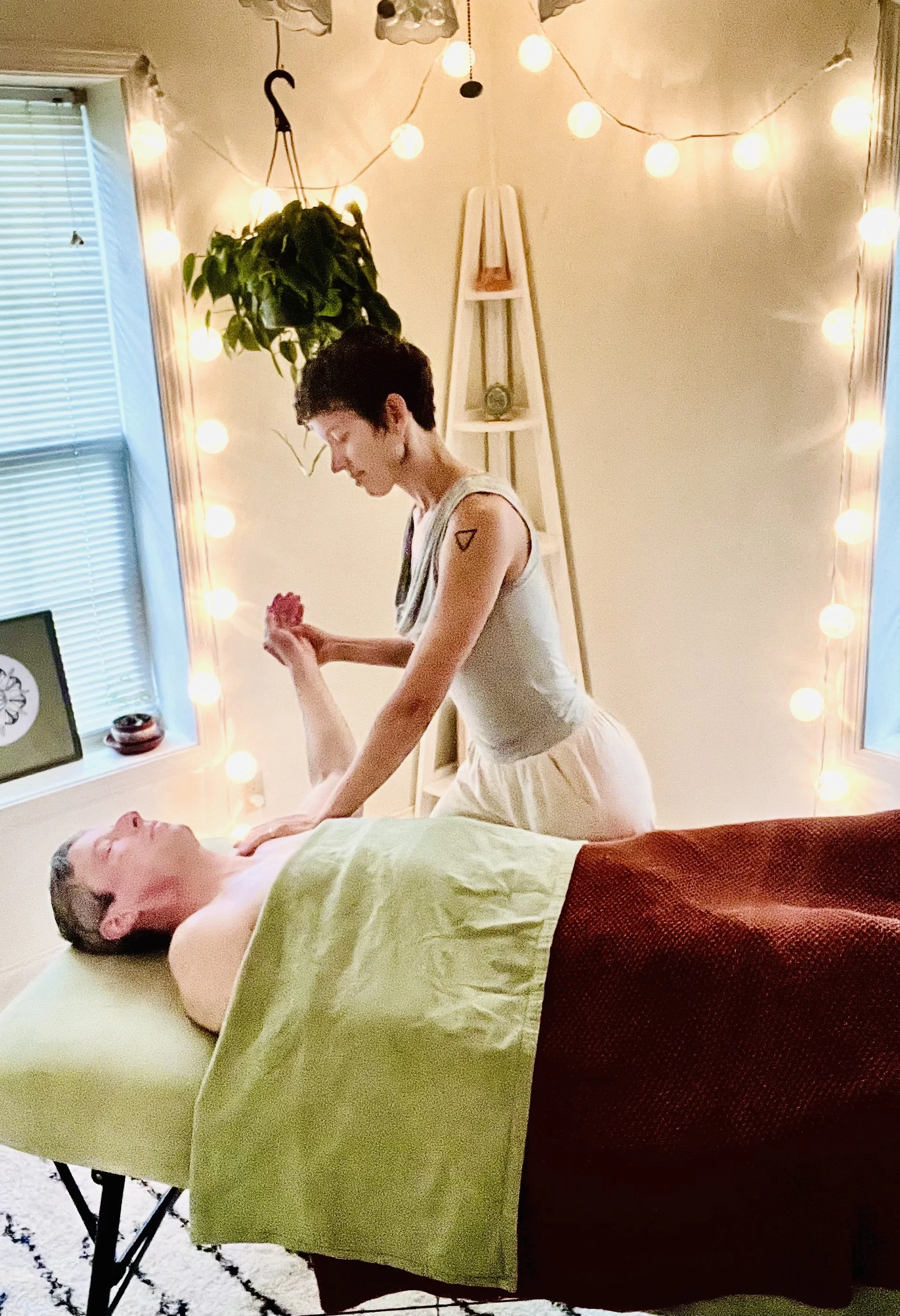 Person receiving a massage in a sunlit room with a window and a potted plant nearby.