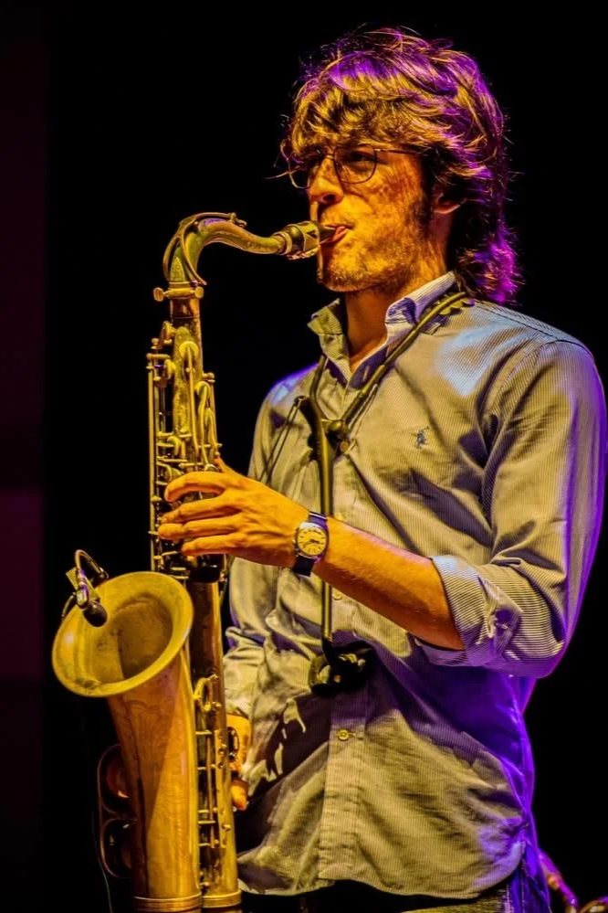Professional saxophone player performing on a concert stage with dramatic cinematic lighting and high-energy production for a large-scale event. Location: Orlando