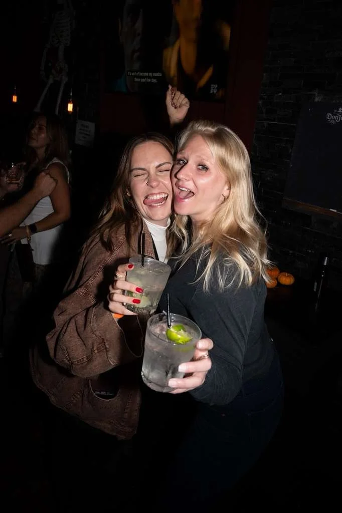 Two women enjoying drinks and having fun at a bar or nightclub.