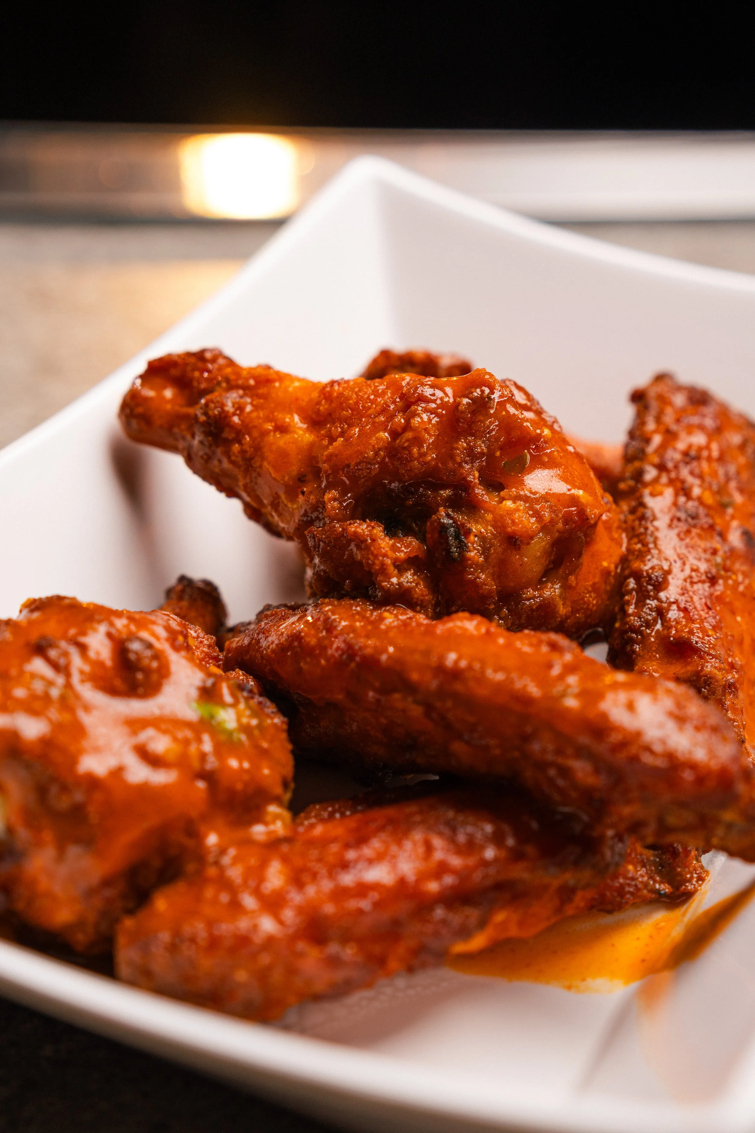 Spicy buffalo chicken wings on a white plate.
