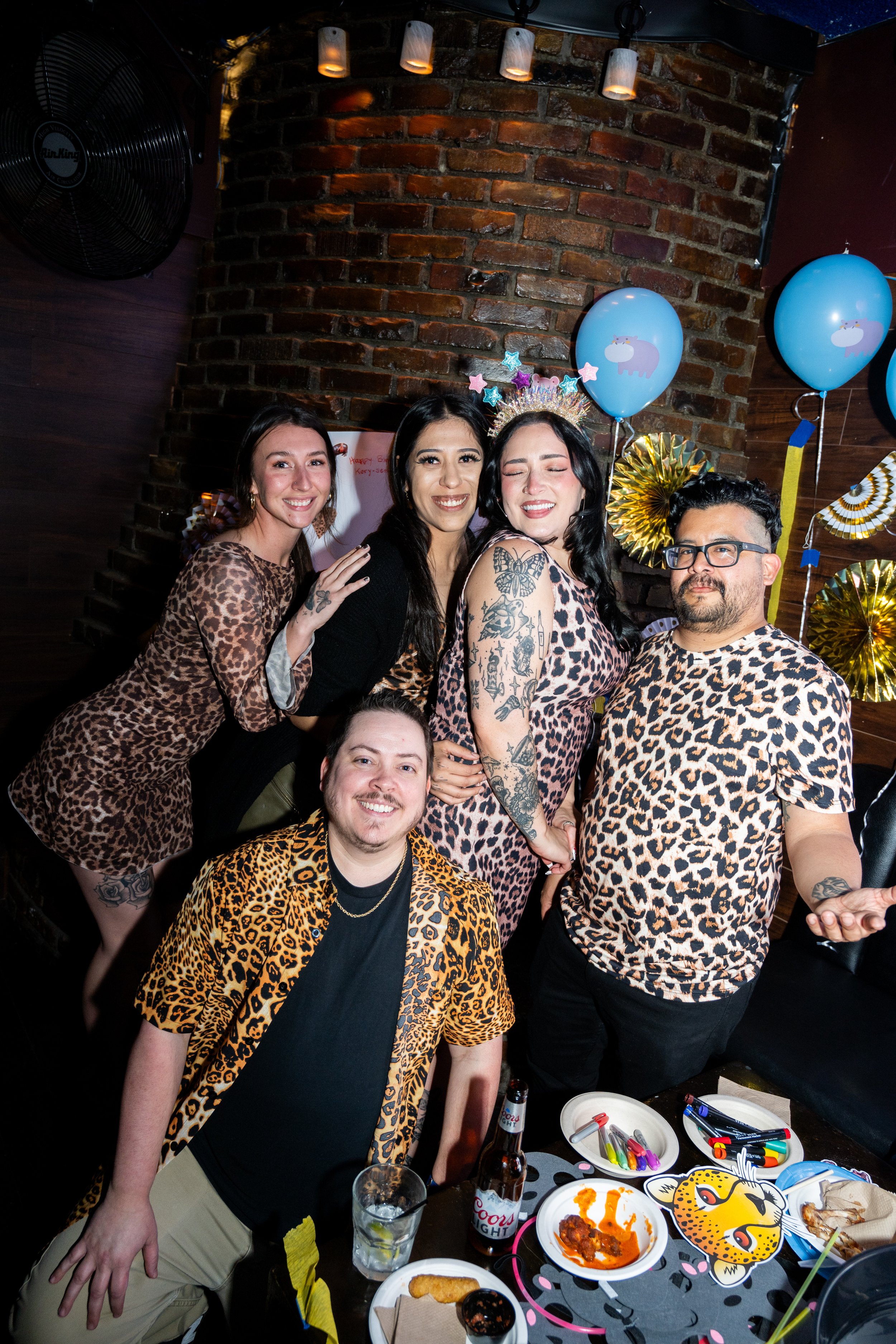 Group of people in leopard print clothing posing at a party with decorations and snacks.