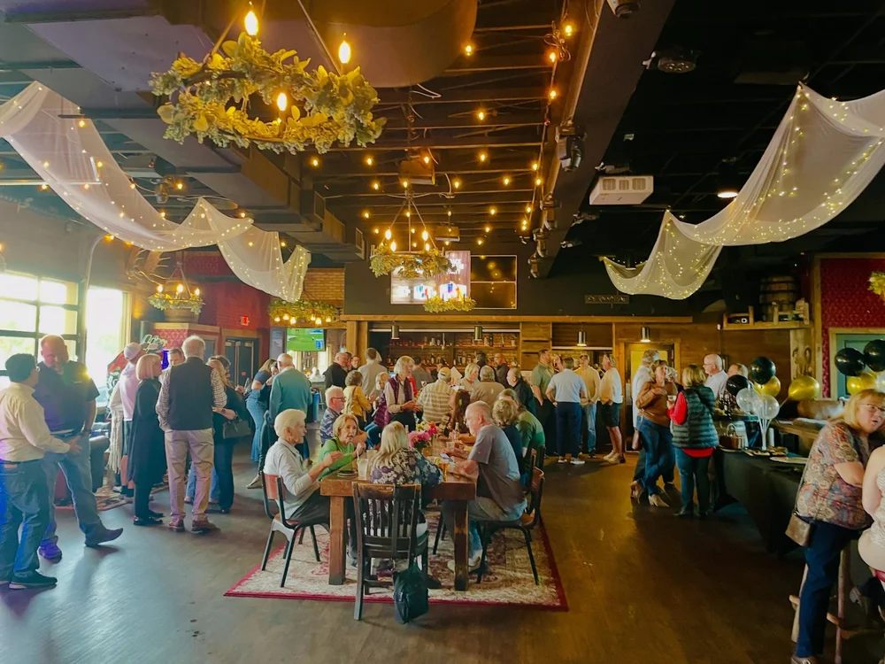 A retirement party filling The Barn under string lights