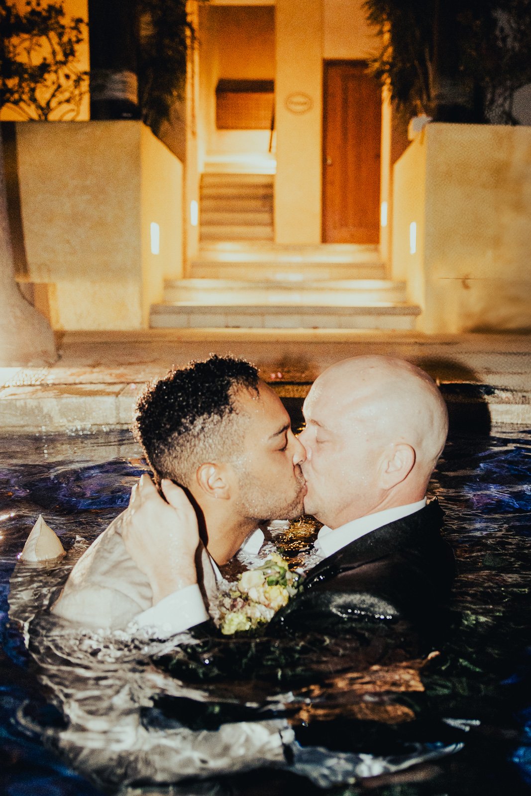 Grooms share a romantic kiss in the pool during their Cabo destination wedding, captured by a Los Angeles-based LGBTQ+ wedding photographer.