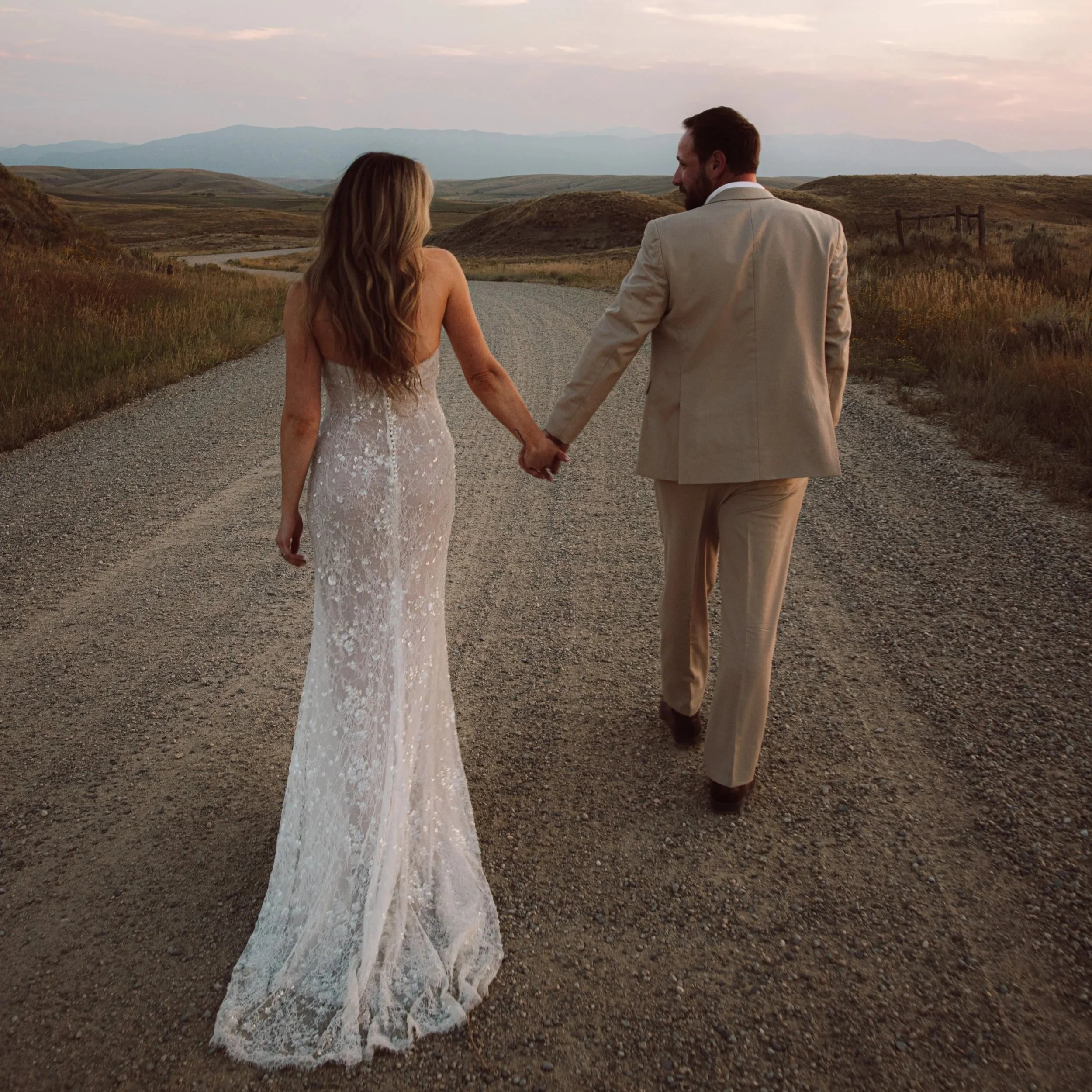 Documentary-style wedding photo of a couple walking into the distance at golden hour, with natural light, candid emotion, and wide-open landscapes.
