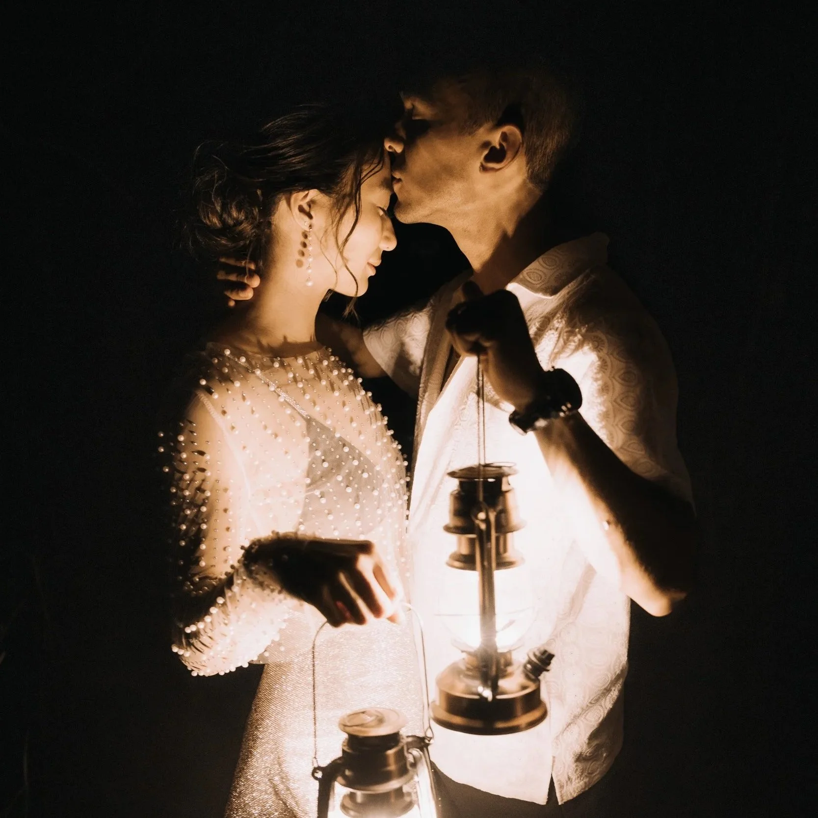 Couple holding lanterns and sharing an intimate moment at their Montana wedding, photographed outdoors at night.