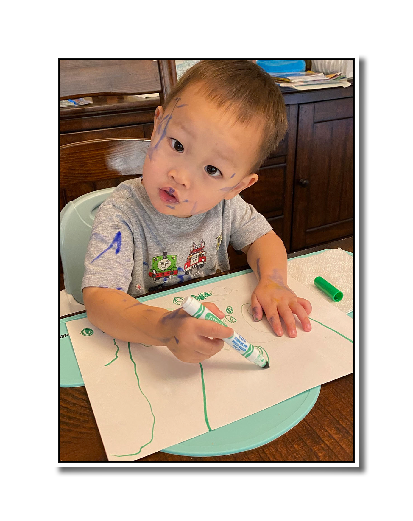Noah coloring with markers, including marks on his face