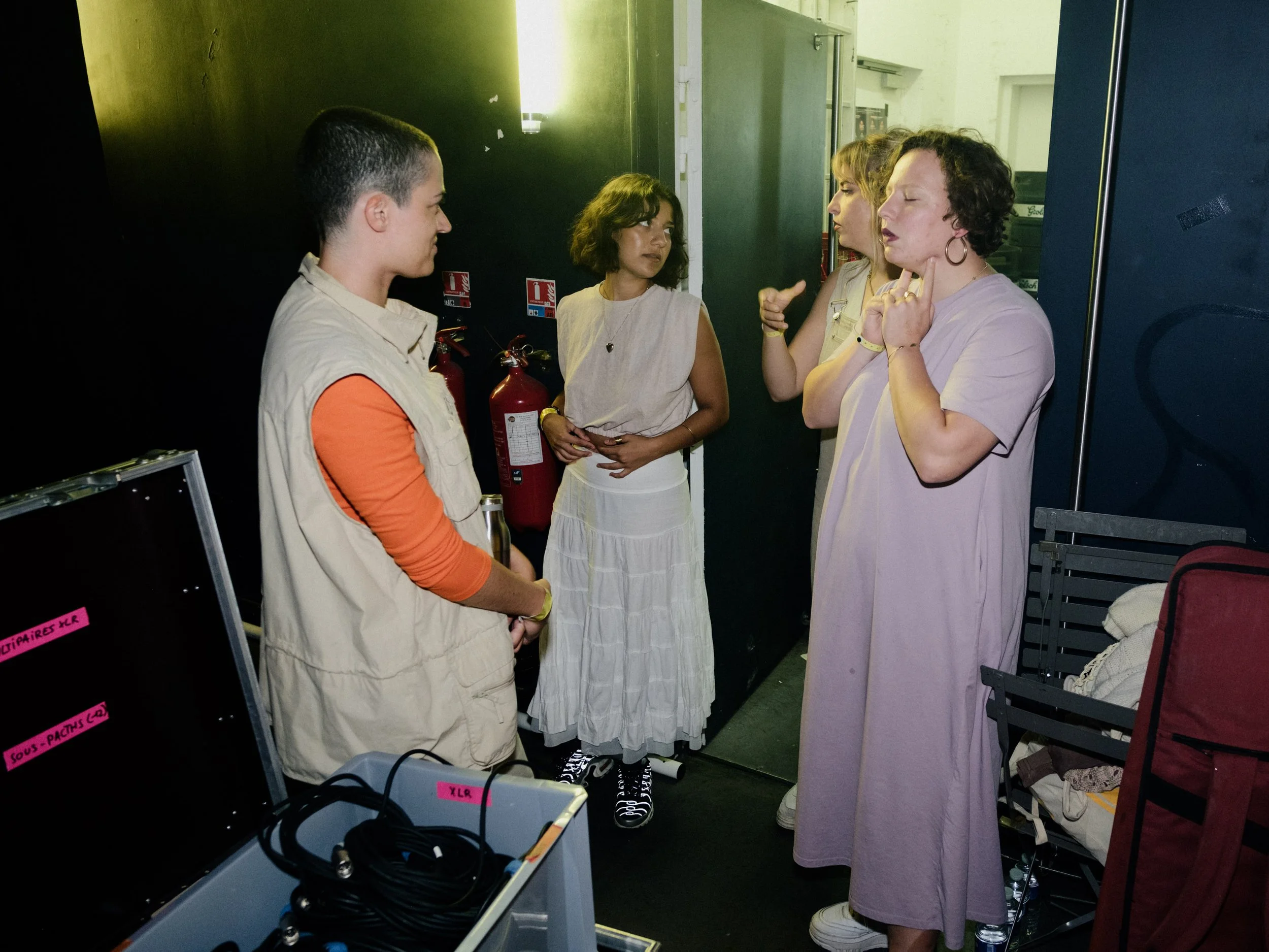Five women having a serious conversation indoors, three of them are speaking while the other two listen attentively.