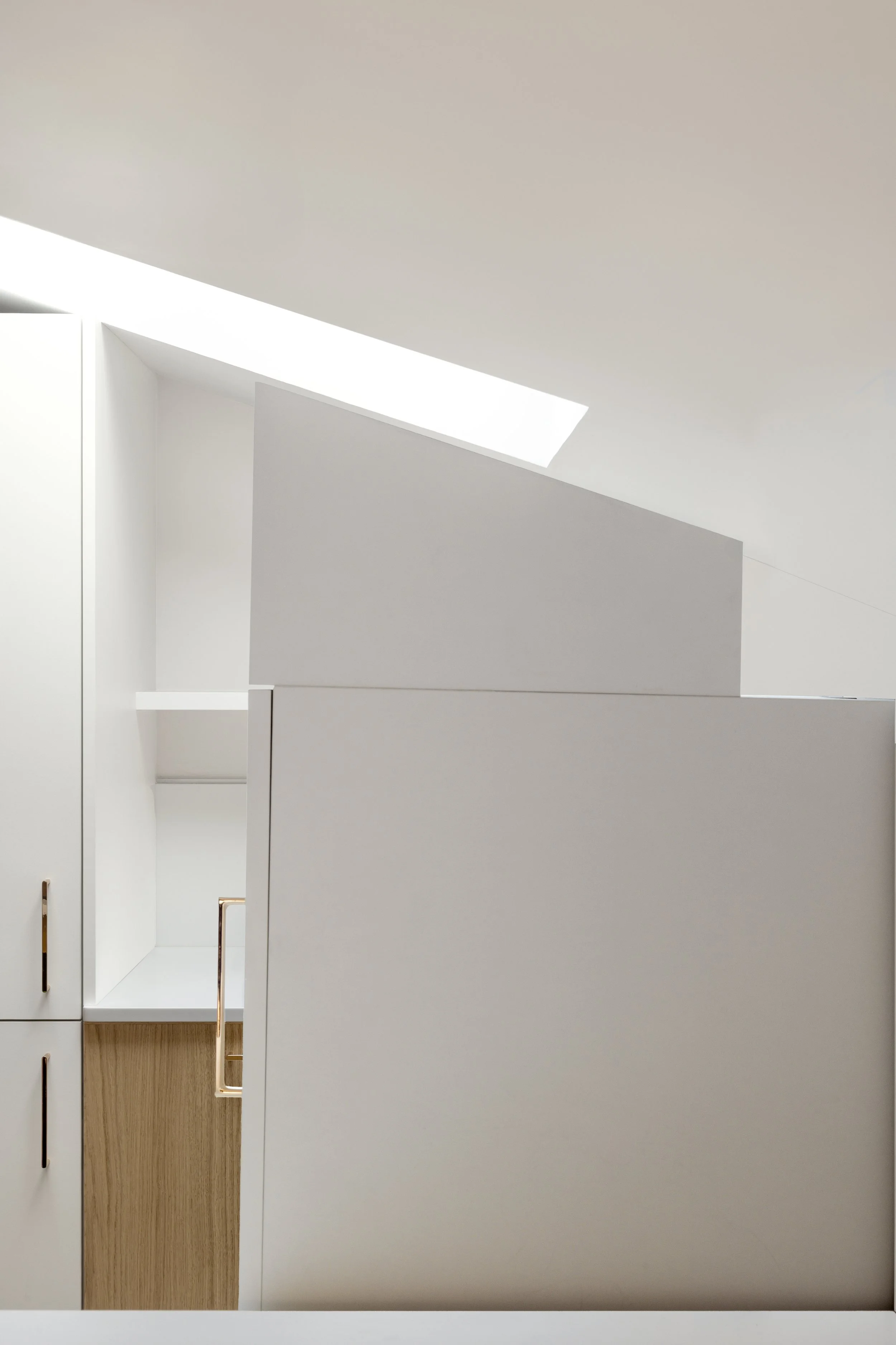 cuisine sur mesure sous pente Velux meuble à roulette plan de travail et crédence en résine Corian Krion blanc évier IKEA étagère avec LED poignée de placard La Quincaillerie bois aggloméré mélaminé décor teinte chêne clair panier de fruits livre de 