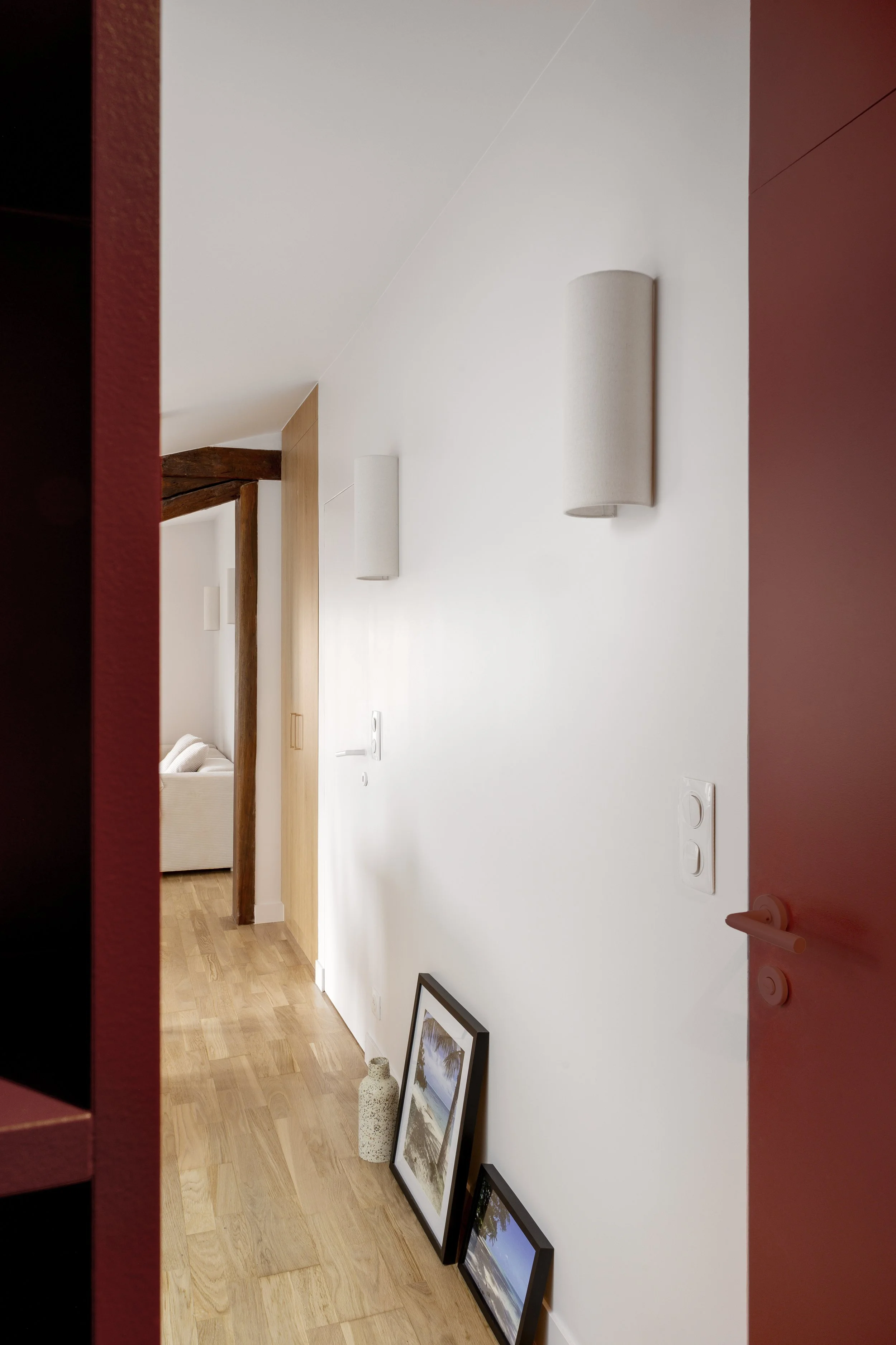 appartement sous-combles rénovation entrée rouge placard sur mesure parquet poncé et vernis interrupteur Legrand  bois agggloméré mélaminé décor bois porte cadre invisible luminaire applique murale Sklum poutre apparente cadre vase poignée de portes 