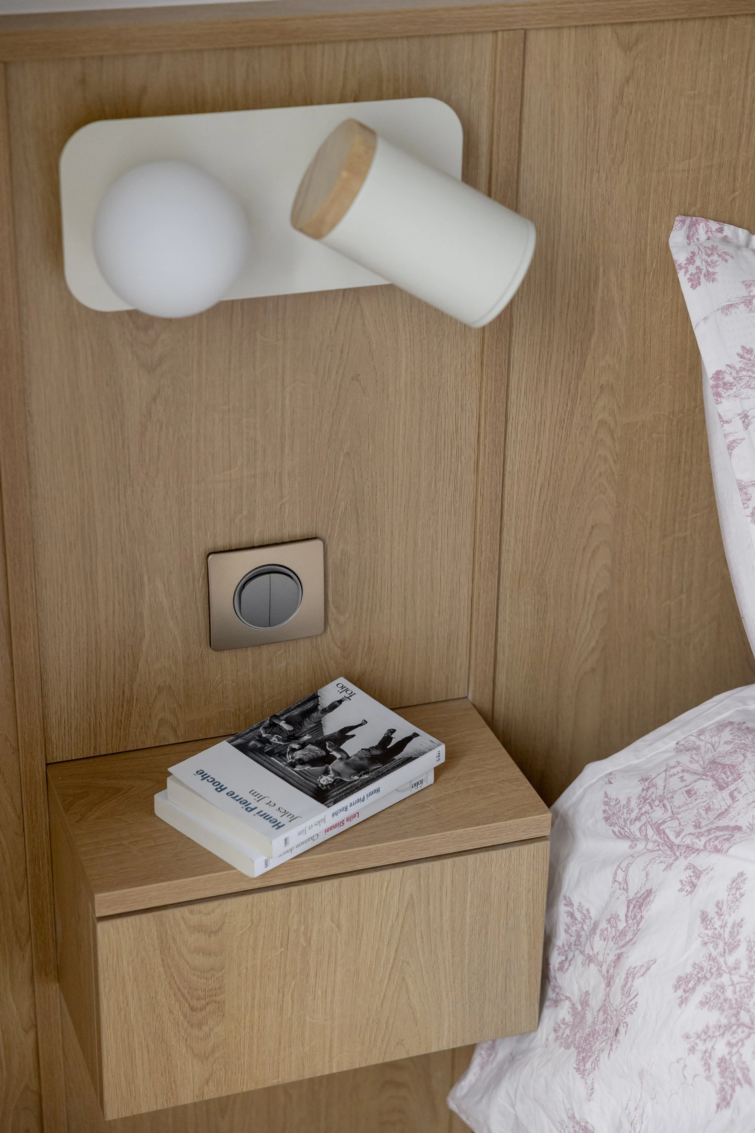 détail constructif tête de lit sur mesure bois aggloméré mélaminé décor bois chêne teinte claire table de chevet tiroir tablette interrupteur Céliane Legrand applique murale liseuse Sklum beige sphère lumineuse spot drap blanc et rose oreiller 