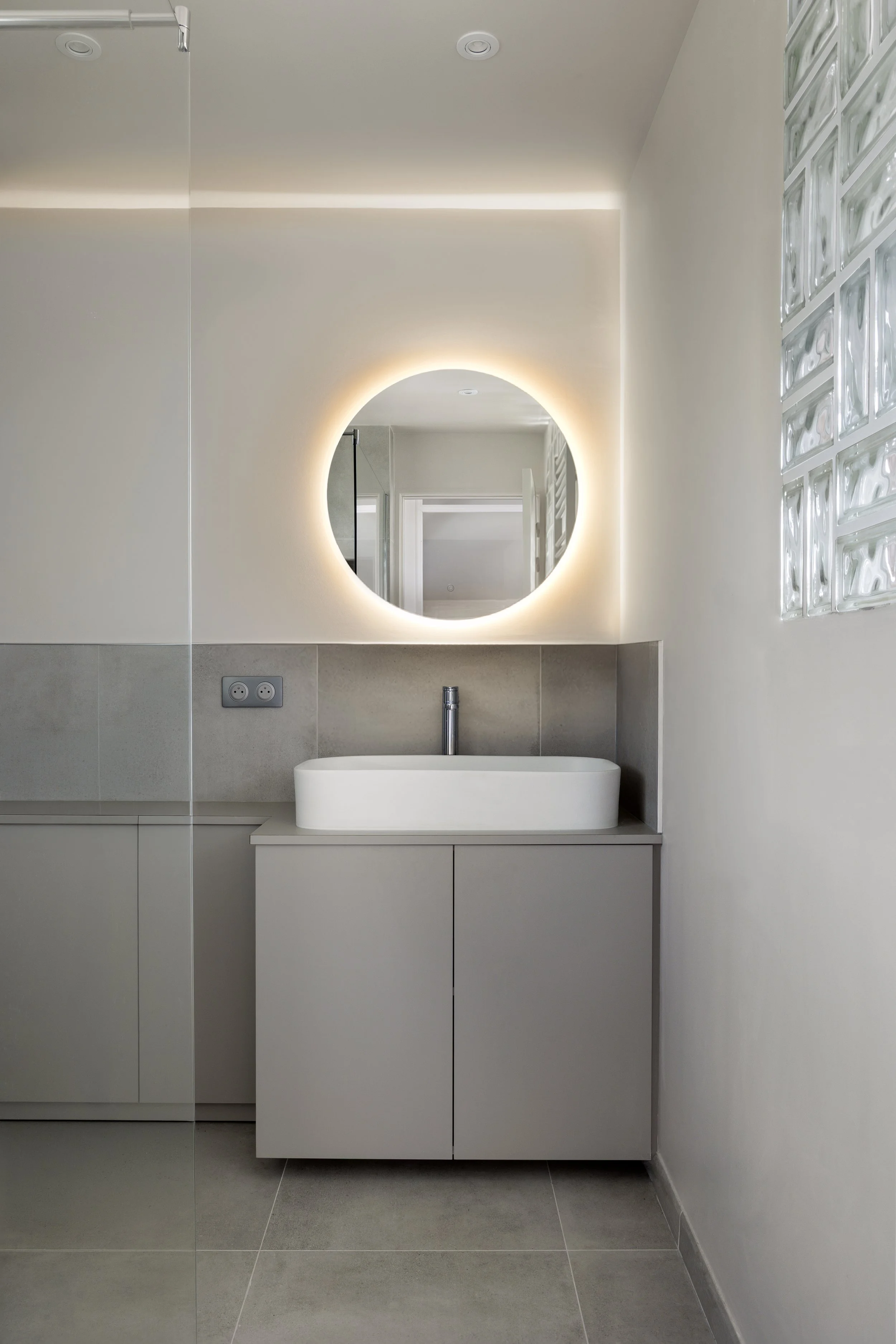 salle de bain aevc rangement sur mesure placard wc niches carrelage effet béton gris clair vasque à poser rectangulaire en céramique miroir éclairé briques de verres robinetterie hansgrohe paroi de douche en verre interrupteur Legrand