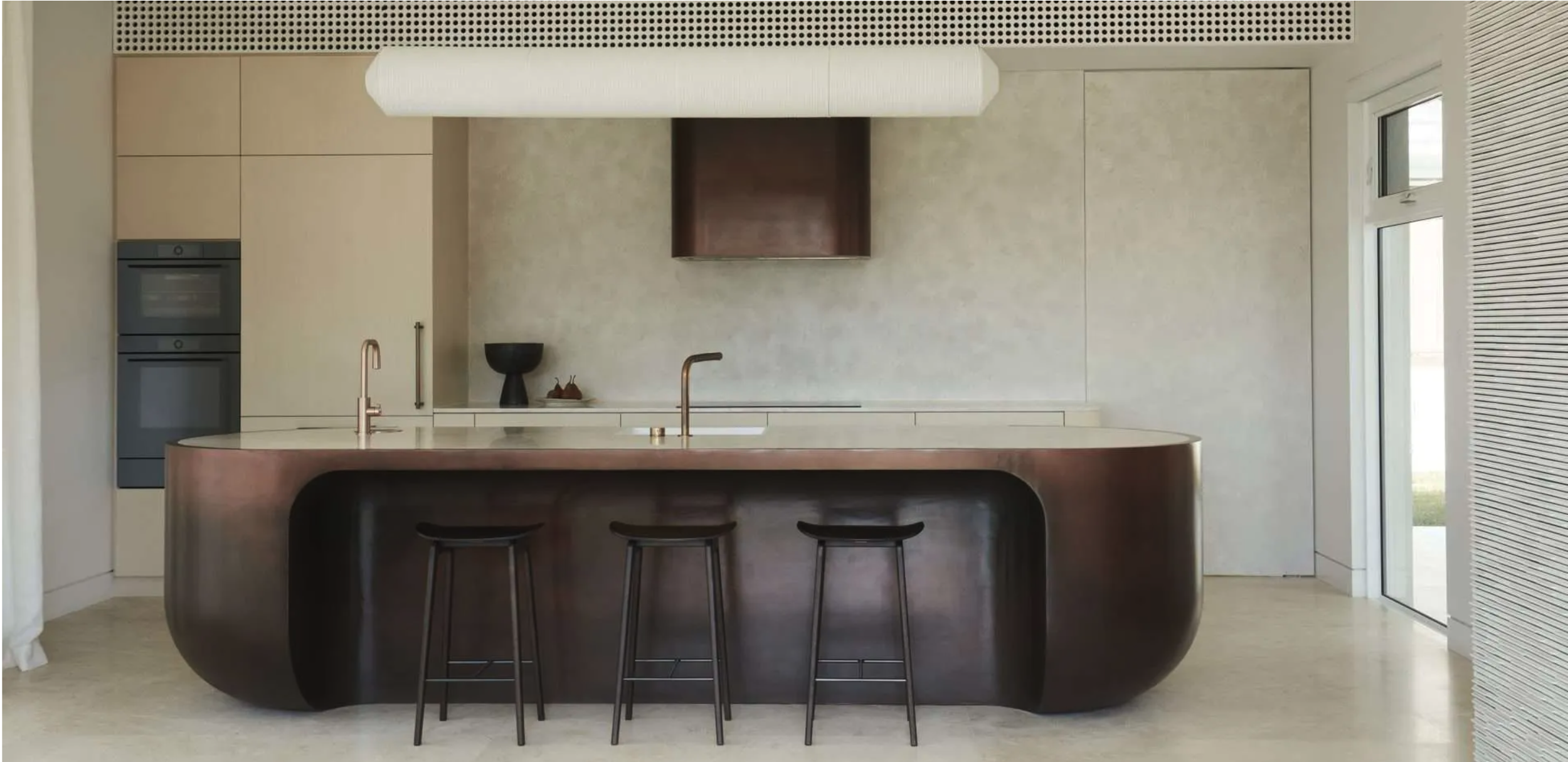 Minimalist kitchen with a curved island, bar stools, and modern appliances.