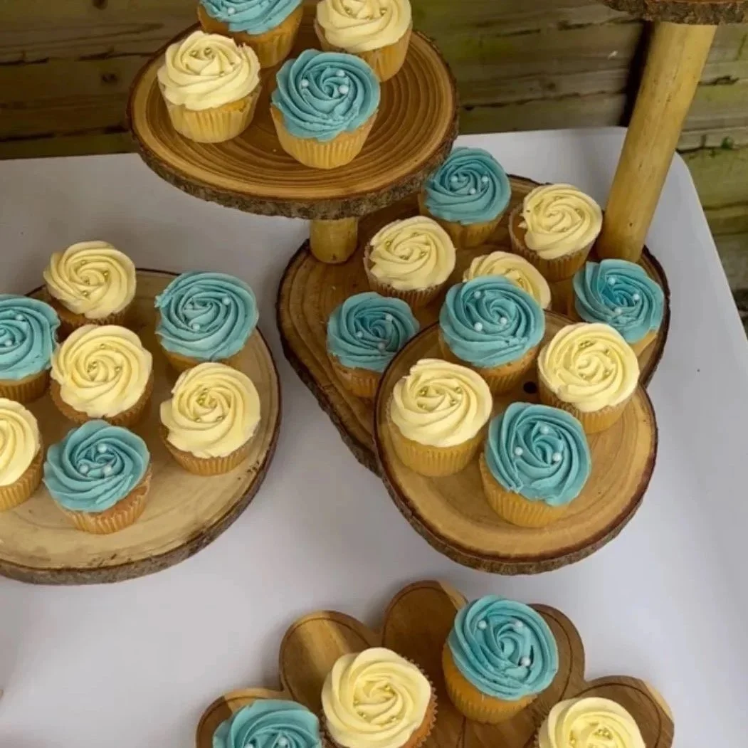 Cupcakes decorated with yellow and blue swirled frosting on wooden tiers and slabs.