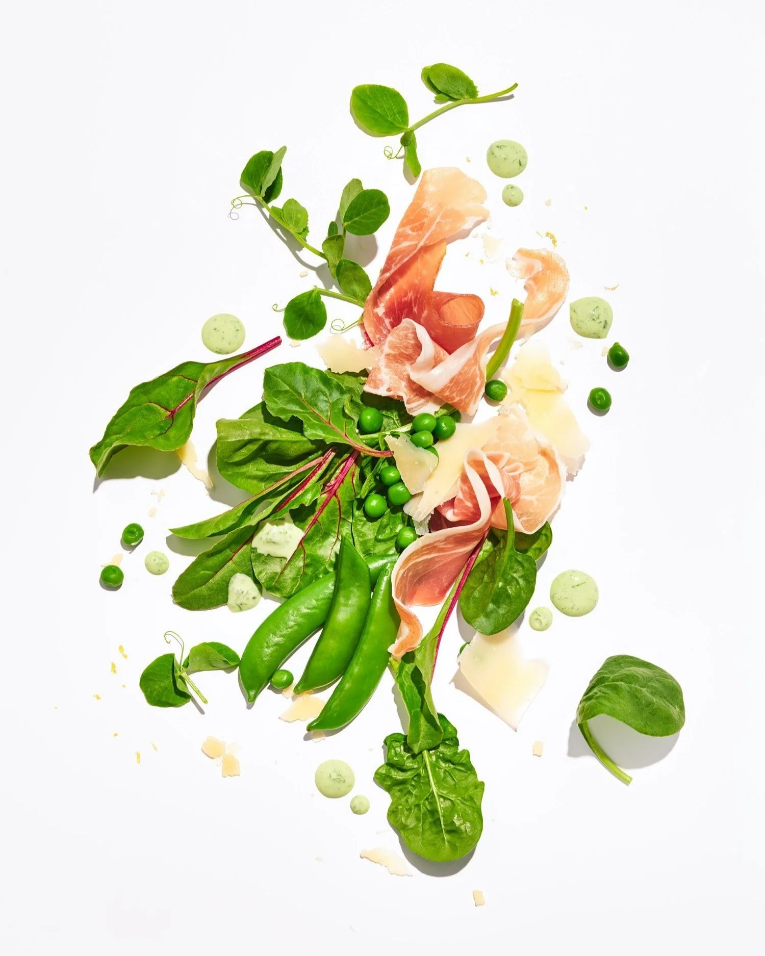 Peas and prosciutto shot on a white background in an artistic way by food photographer Frankie Turner