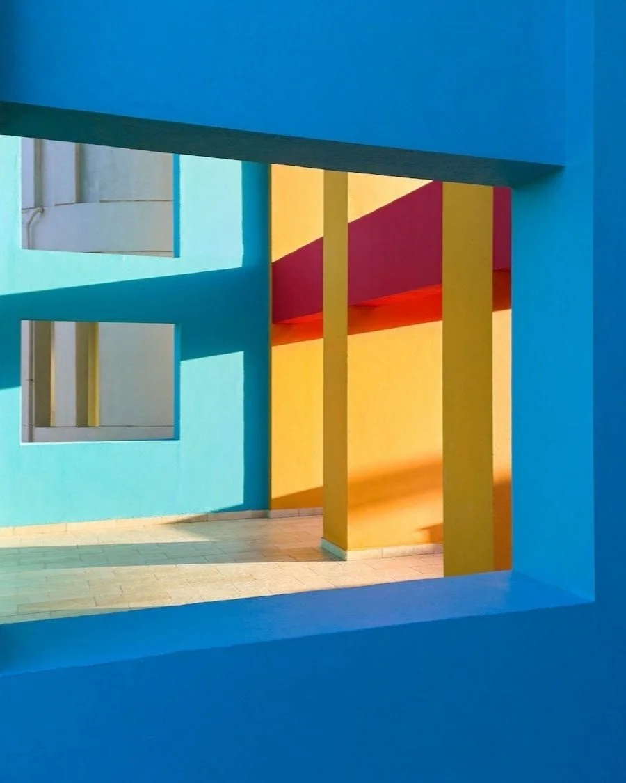 Geometric view through a blue window frame revealing bold yellow and red columns against turquoise walls, captured by optical illusion photographer Joseph Ford in a vividly coloured Egyptian waterpark