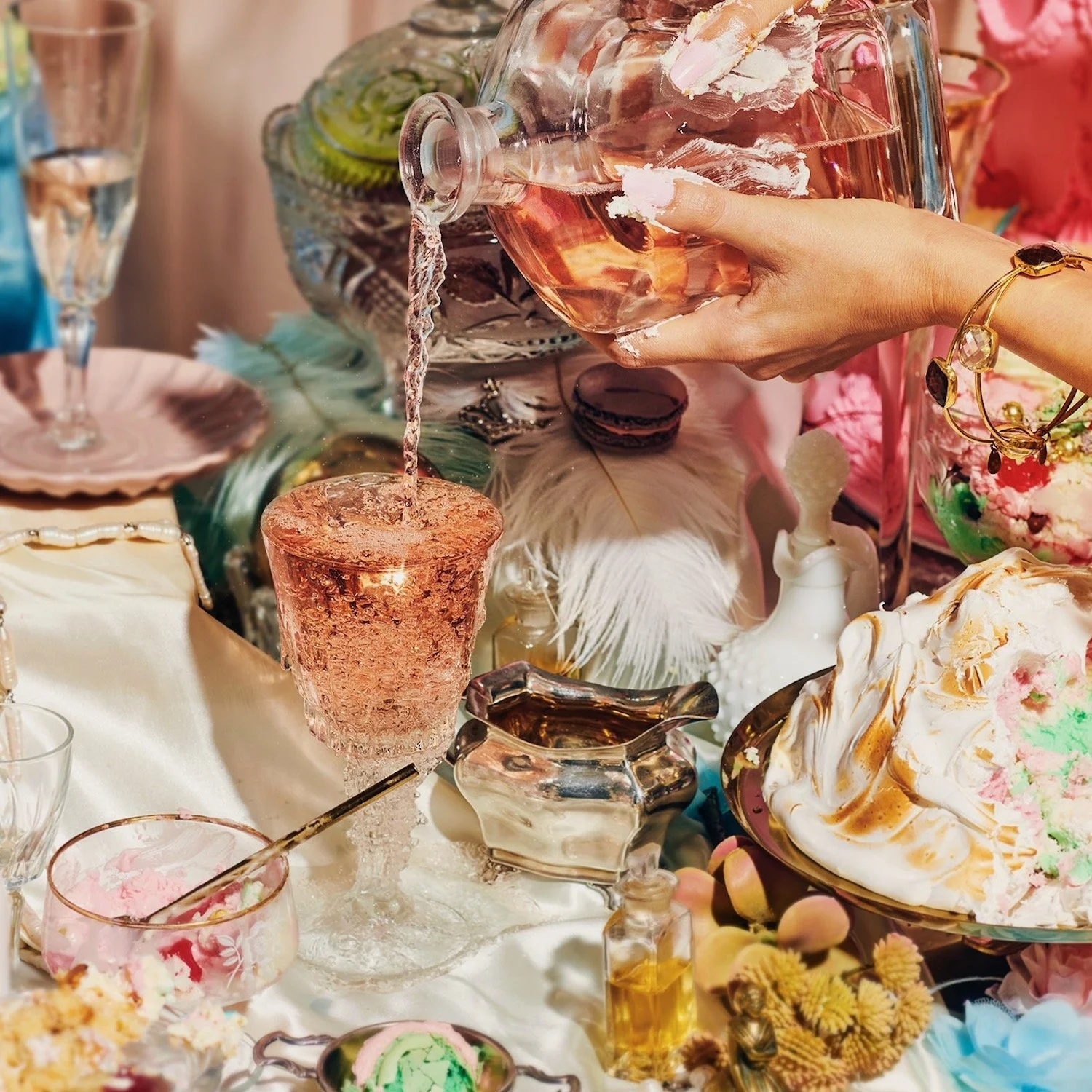 Wine being poured into a glass on a table laden with cake and desserts, drinks photography by Frankie Turner