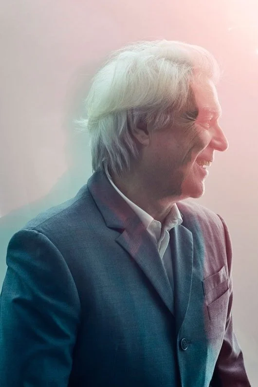 Atmospheric portrait of musician David Byrne in profile, photographed by Phil Fisk in London. Editorial shoot with soft lighting and pastel tones, reflecting Byrne’s creative persona.