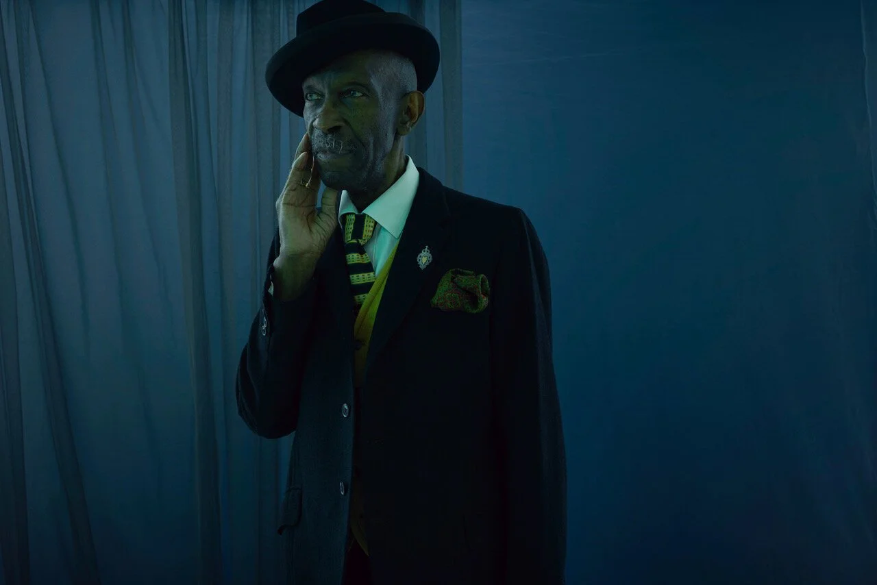 Older man in a dapper suit, shot in moody and theatrical lighting by London-based photographer Phil Fisk