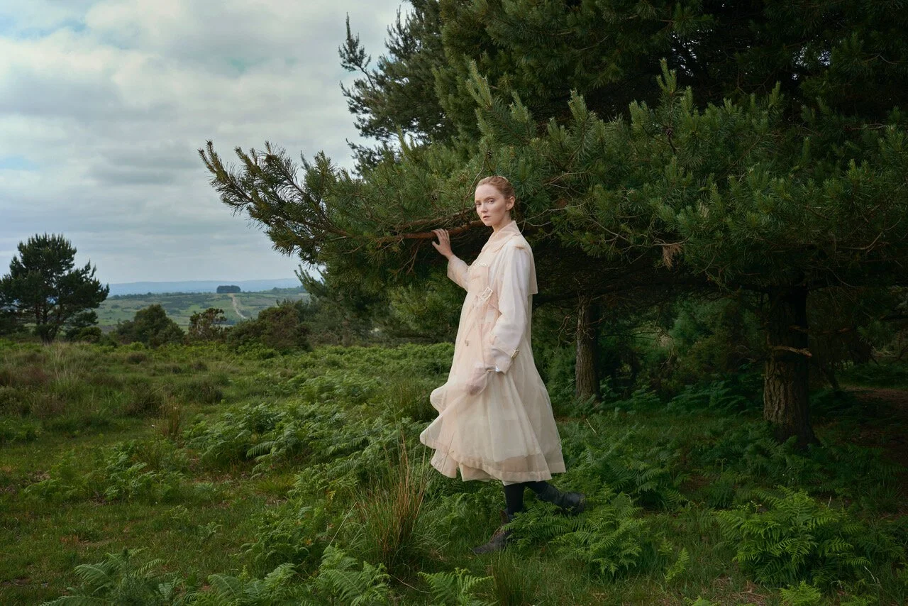 Lily Cole in a sheer vintage dress among pine trees in the New Forest, photographed by Phil Fisk in a conceptual editorial style for The Observer Magazine