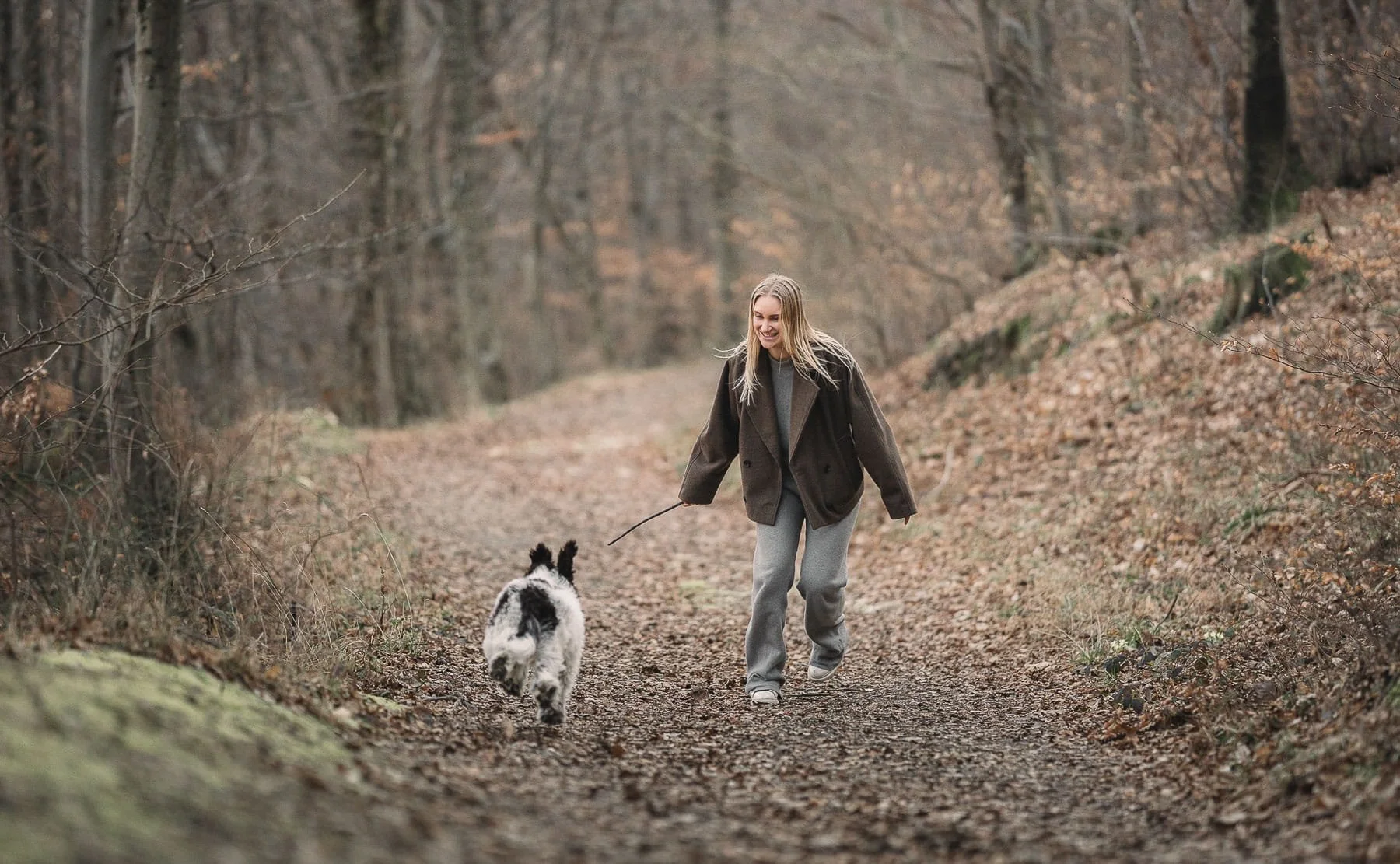 Spontane hondenfotoshoot tijdens een wandeling in het bos, waarbij het plezier en de band tussen hond en baasje op een natuurlijke manier wordt vastgelegd door een hondenfotograaf in de regio Nijmegen.