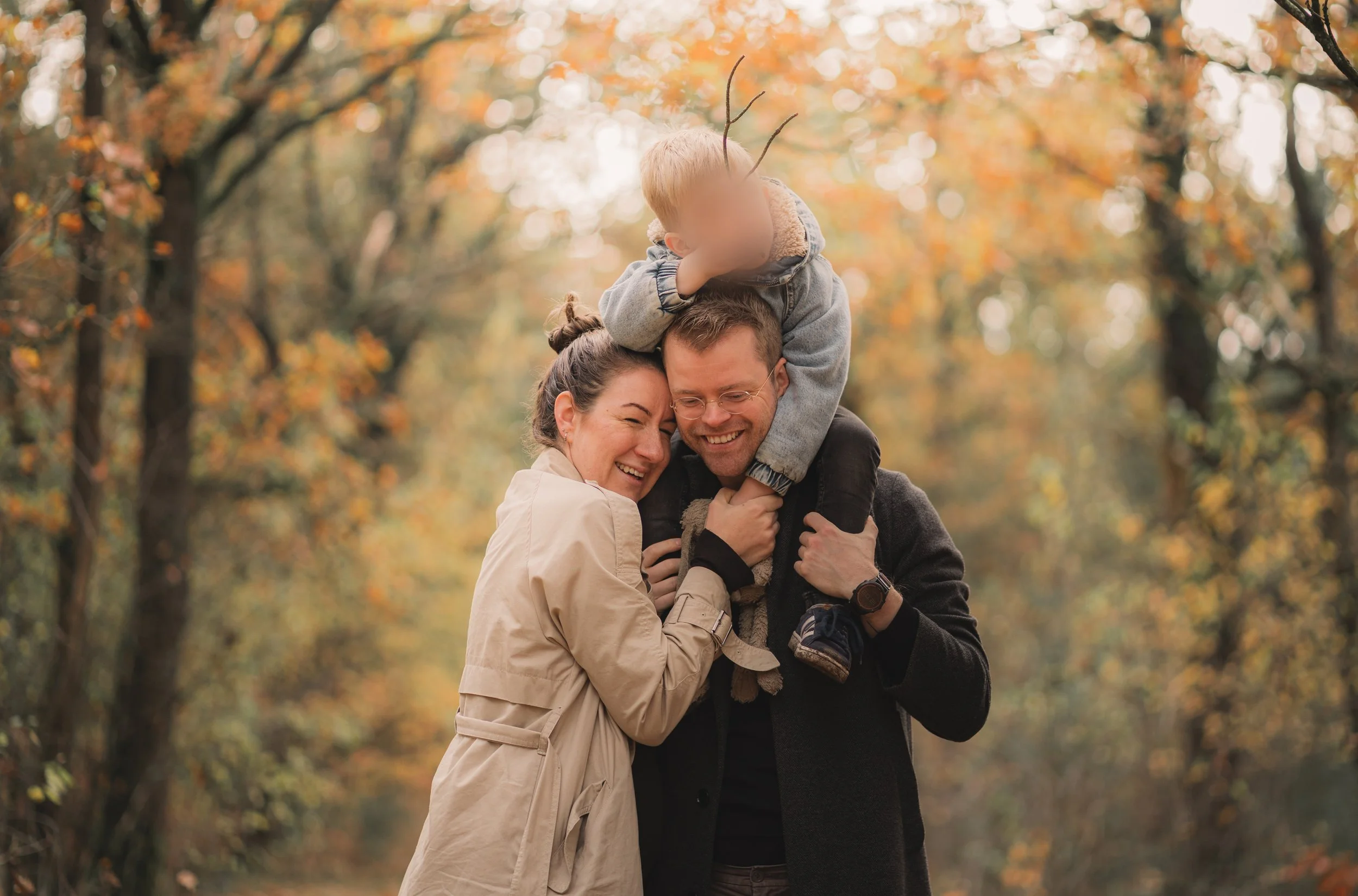 Familie knuffelt en lacht in de herfstkleuren tijdens een gezinsfotoshoot in de Maashorst