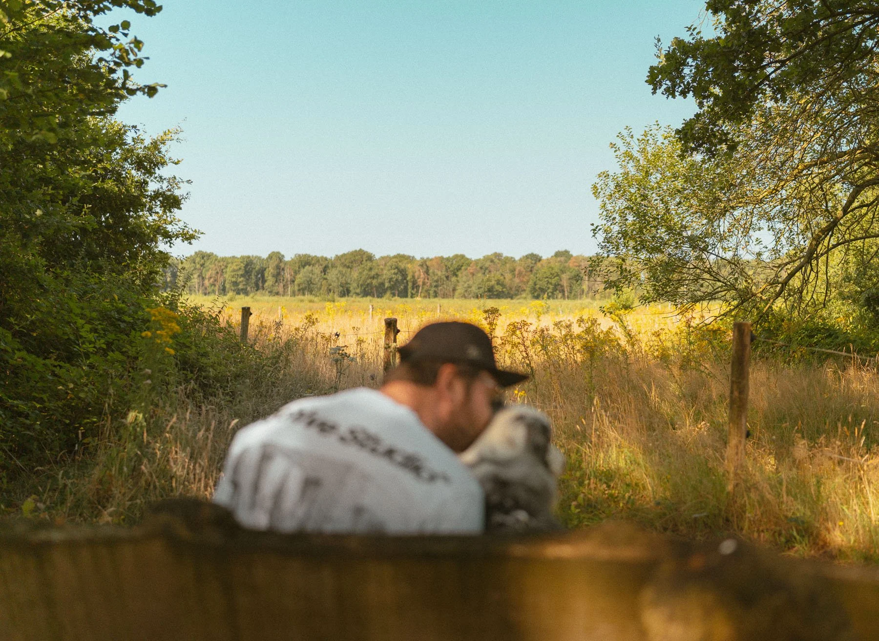 Baasje zit met hond op een bankje in het bos tijdens de Kampina-wandeling