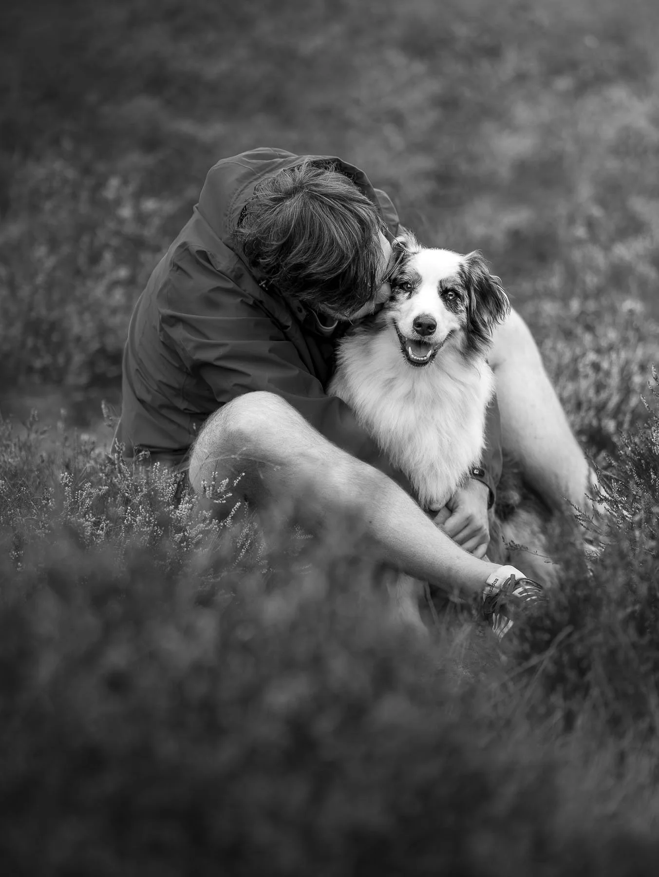 Emotionele zwart-wit hondenfotoshoot van een hond en baasje op de heide in Nederland, waarbij de liefde en band tussen mens en hond centraal staat.
