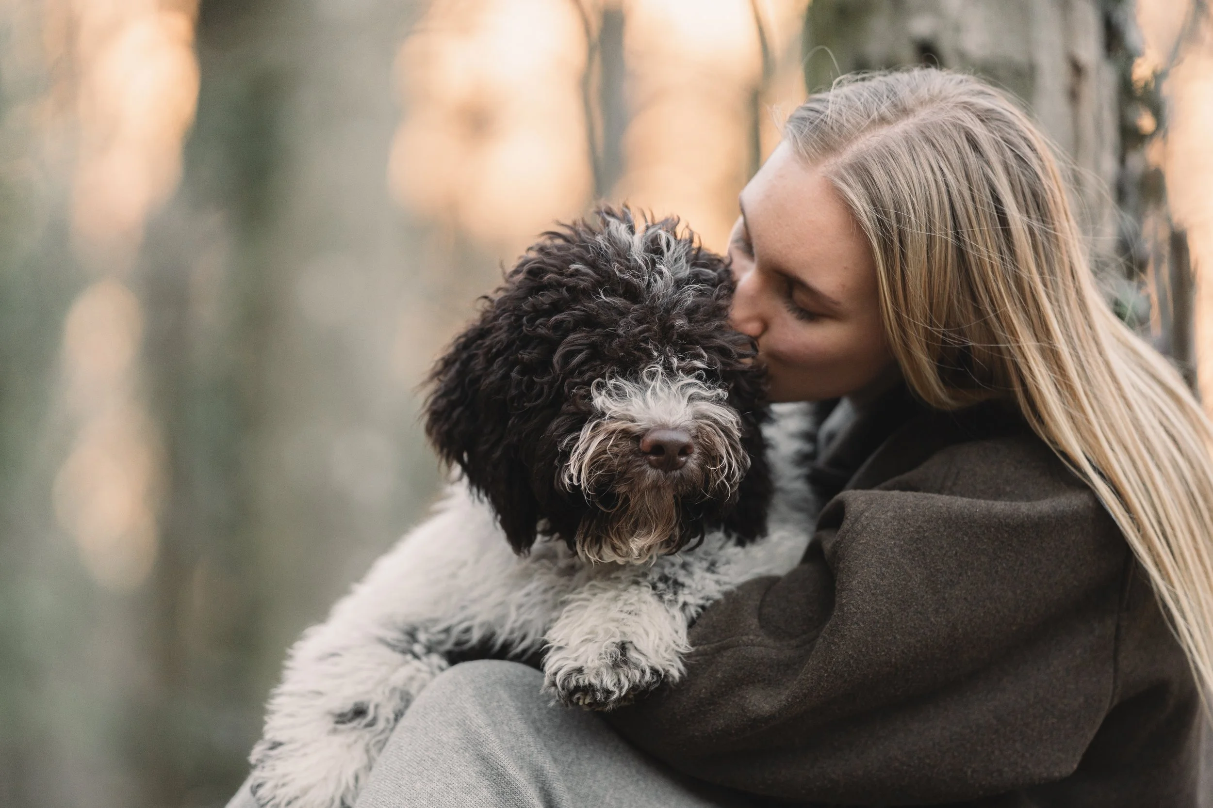 vrouw met lange haren en krulhond in natuurlijk licht met rustige sfeer