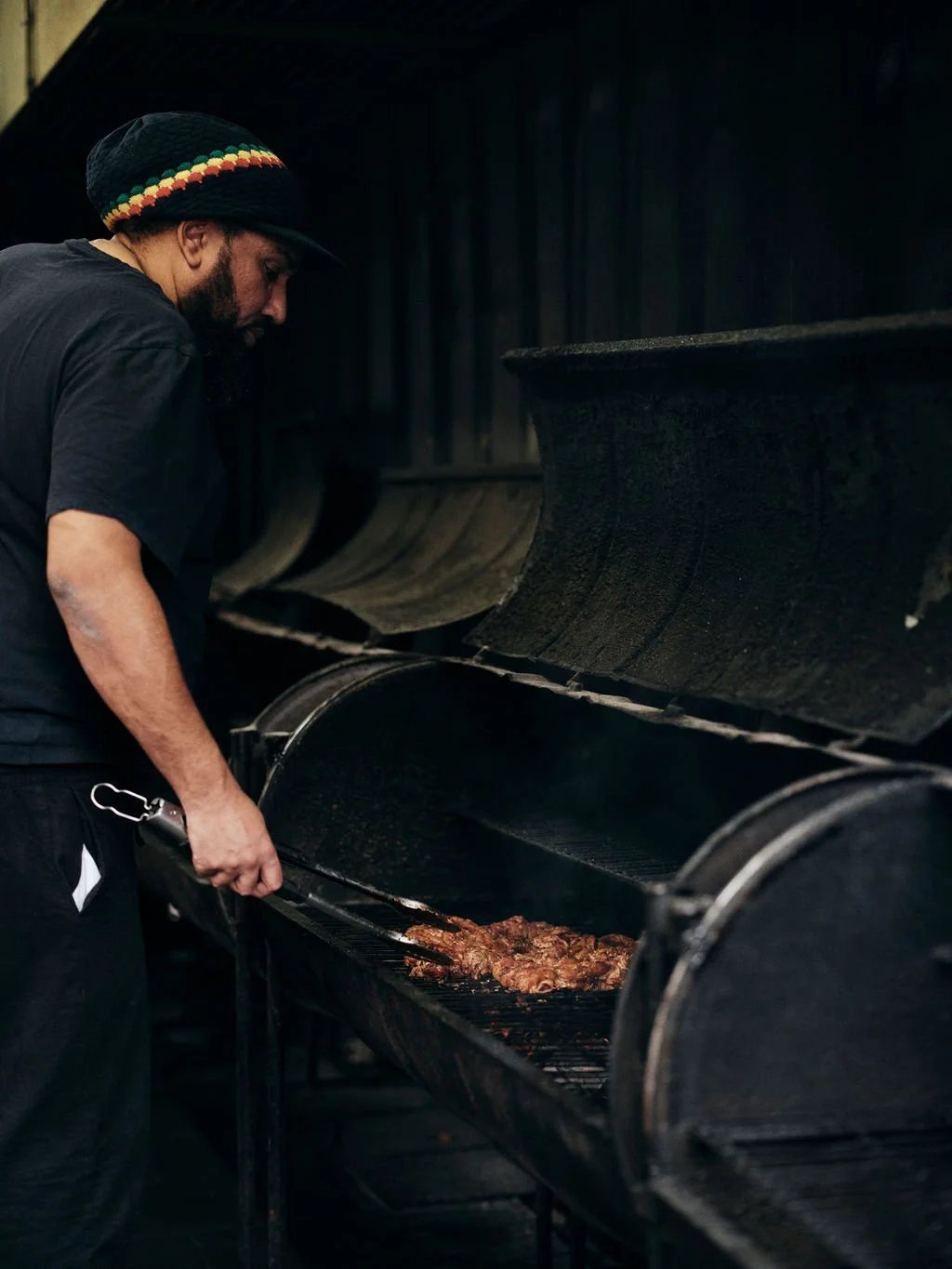 Natty tending food on a large outdoor jerk barbecue