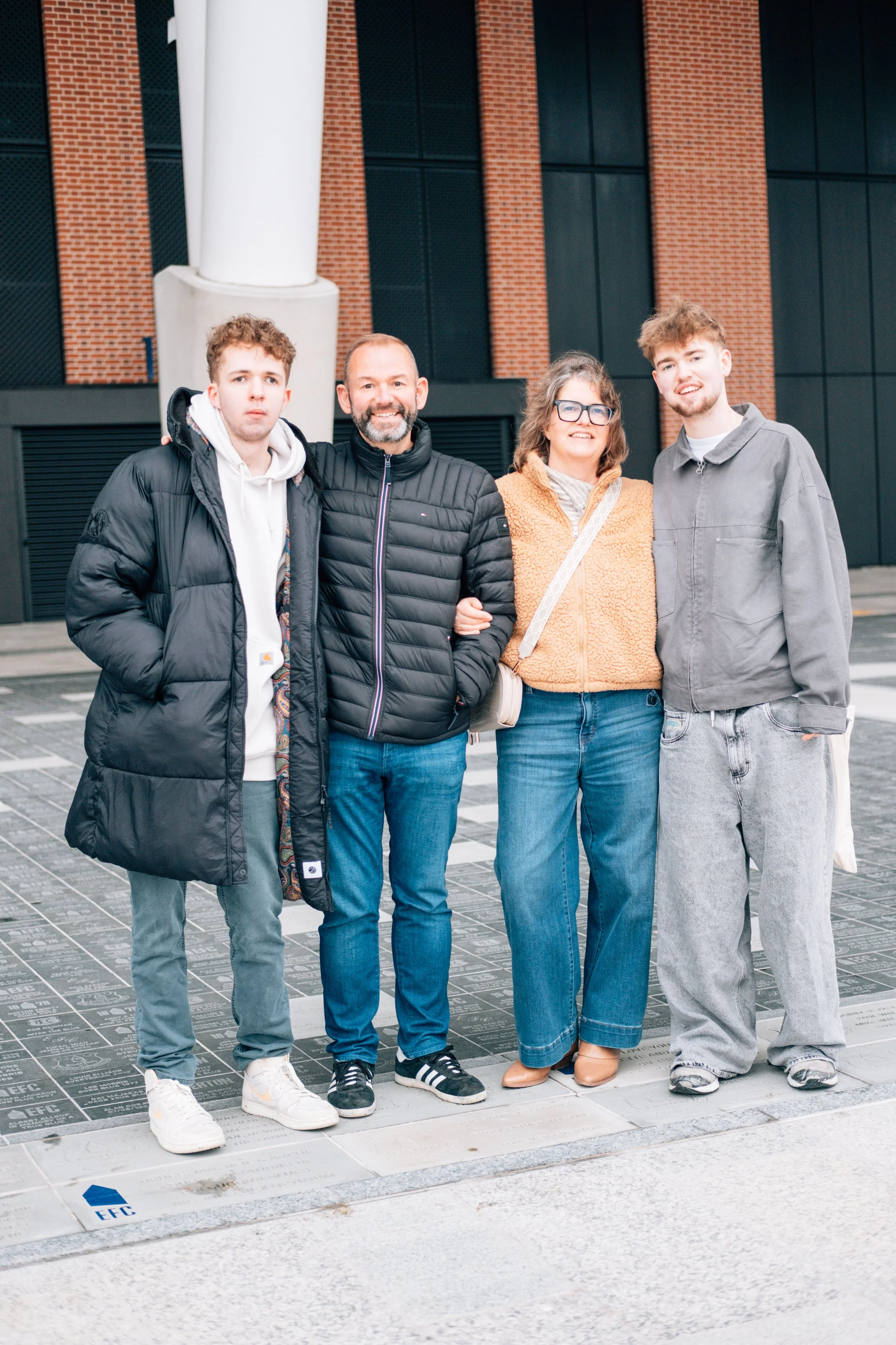 Four people standing outside in front of a modern building, posing for a photo.