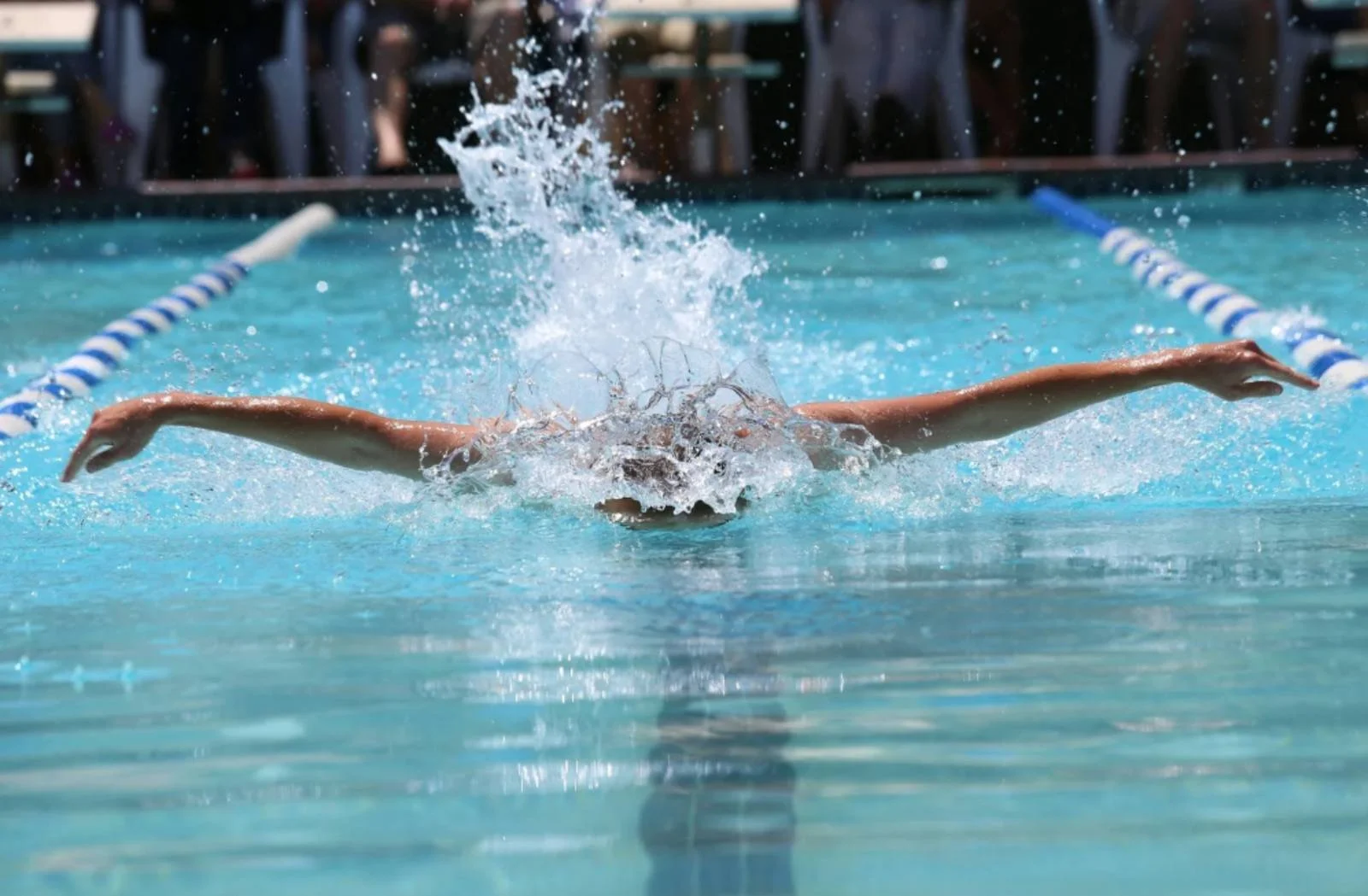 A swimmer pushing through the water in a pool, representing attachment to outcomes and fear of falling short in performance.
