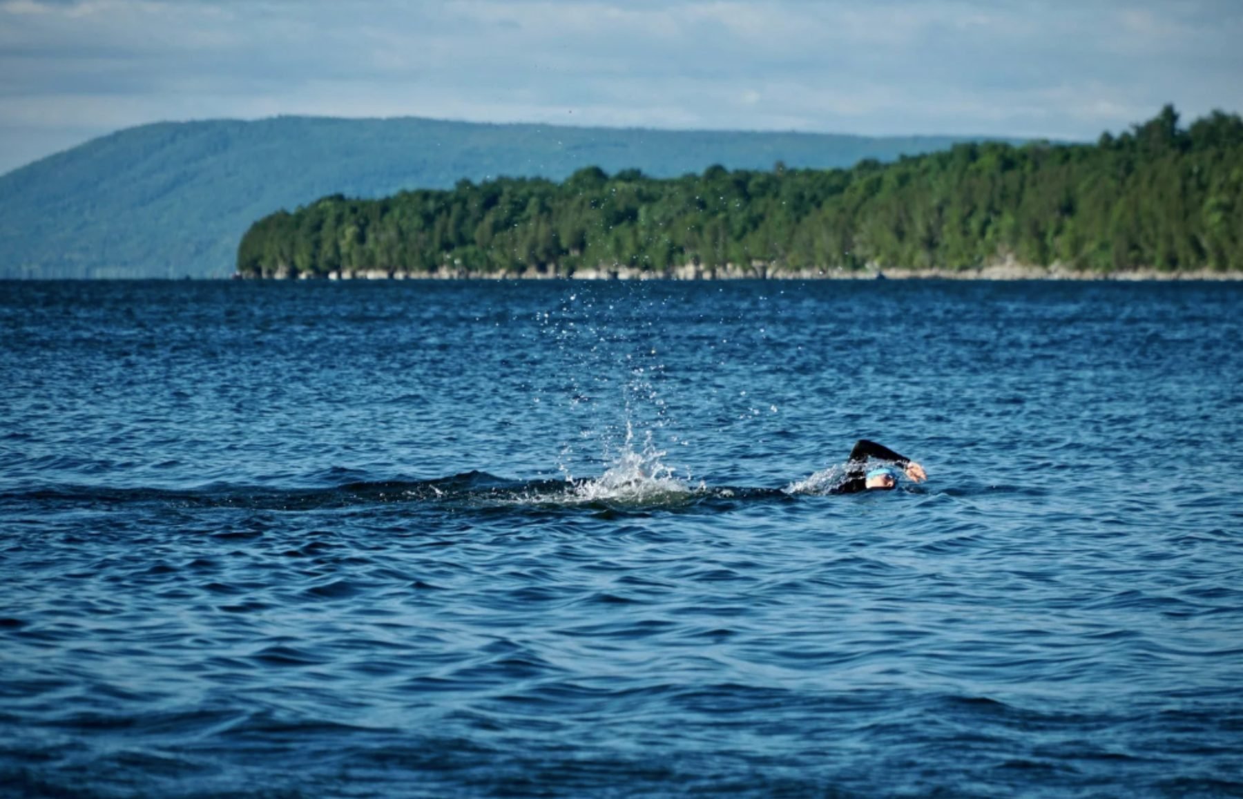 Open water swimmer enjoying training in a lake, reminding athletes to find joy even when training feels hard.