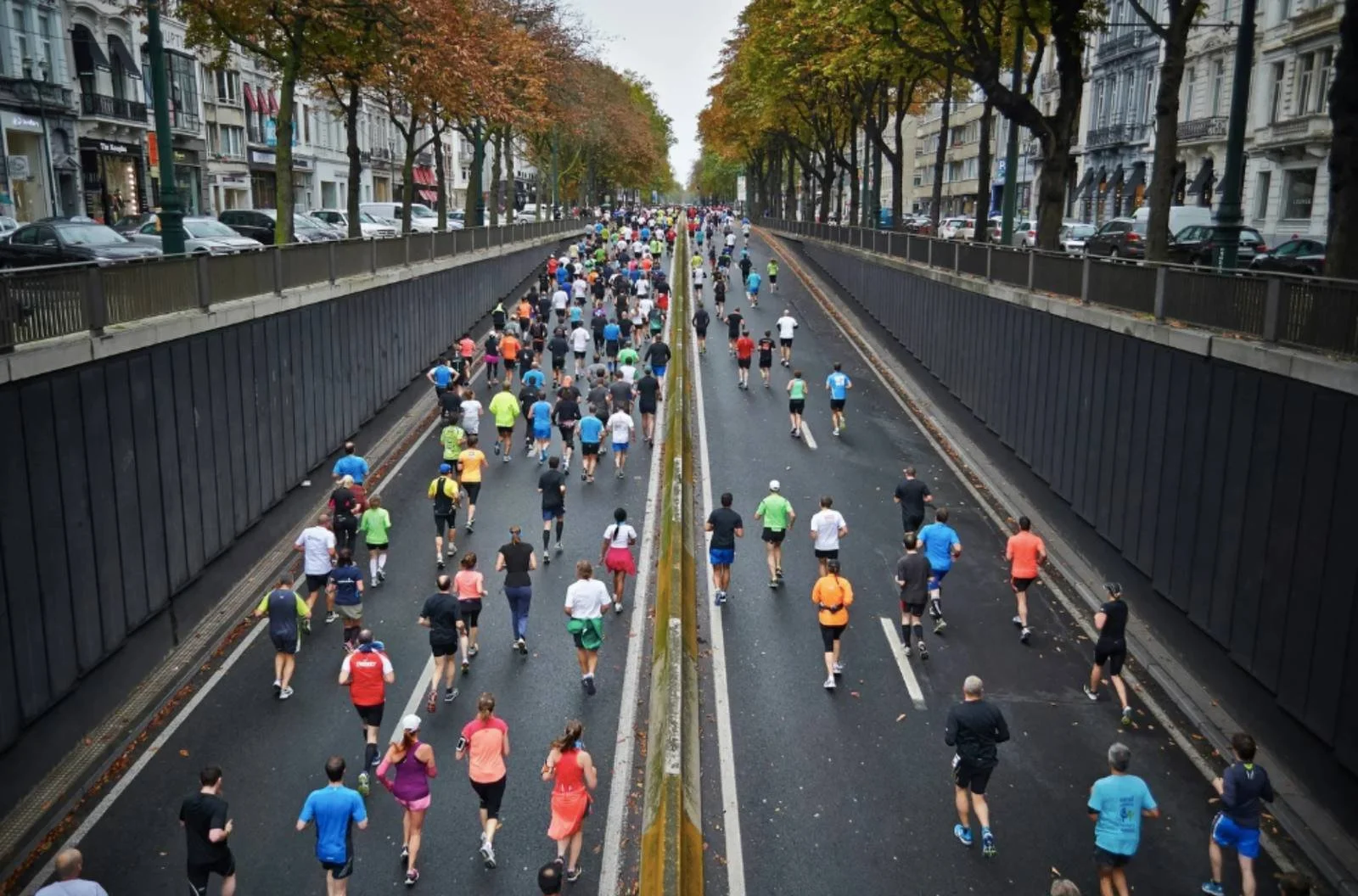 A large group of runners moving through a city course, representing discomfort, avoidance and persistence in long term training.