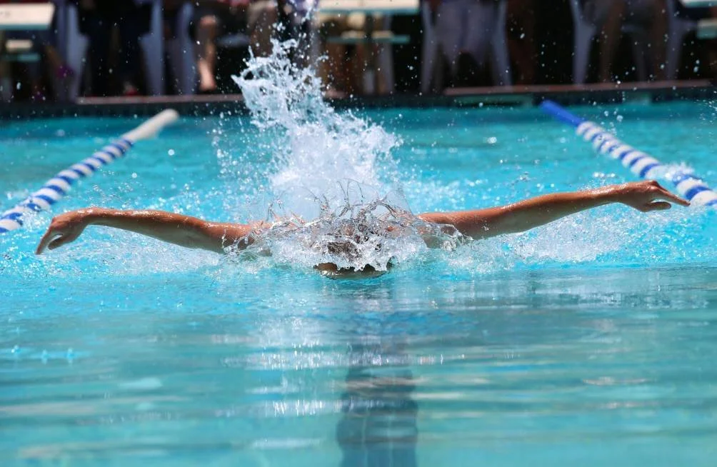 Schwimmer, der während einer Trainingseinheit im Schwimmbad den Schmetterlingsstil ausführt, wobei die Bahnlinien sichtbar sind