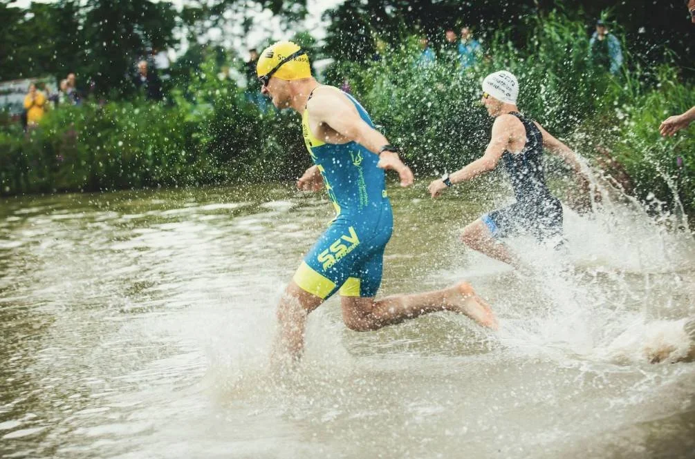 Triathletes beginning the swim leg of a race while using Ironman 70.3 training zones to guide pacing and performance
