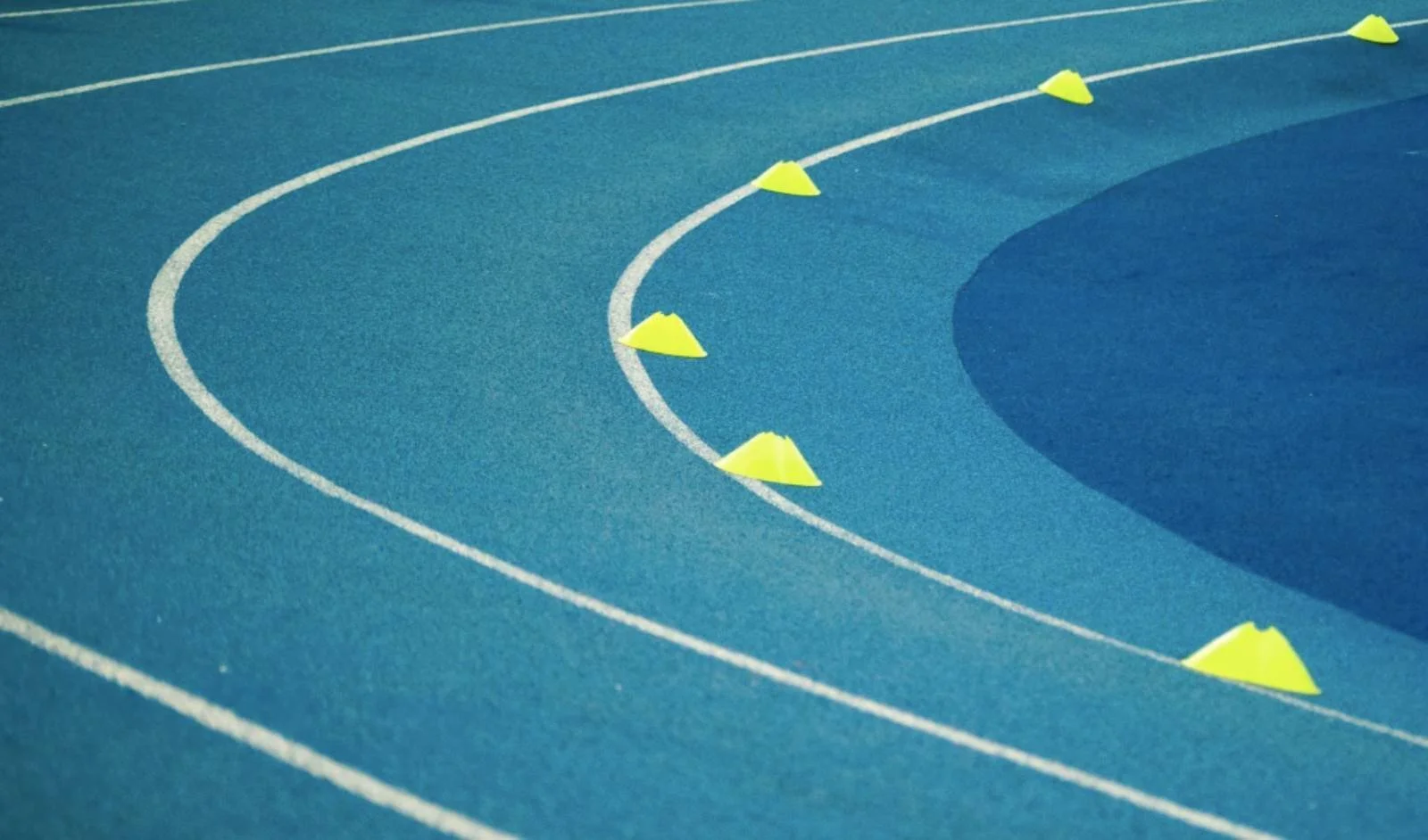 Eine Laufbahn mit Trainingskegeln, die Reflexion und Tagebuchführung symbolisieren, um Vertrauen in Trainingsentscheidungen aufzubauen.