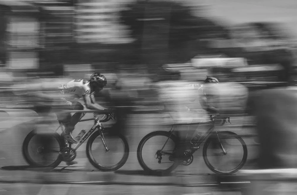 Cyclists riding at speed in a blurred scene, representing patience and trusting long term progress.