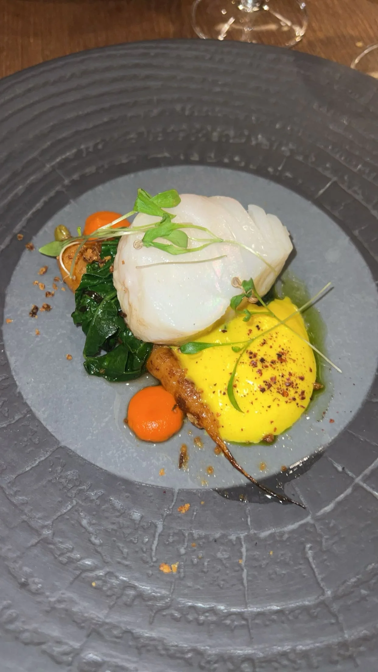 assiette avec un filet de poisson blanc, purée jaune, légumes verts et carottes, décorations végétales.