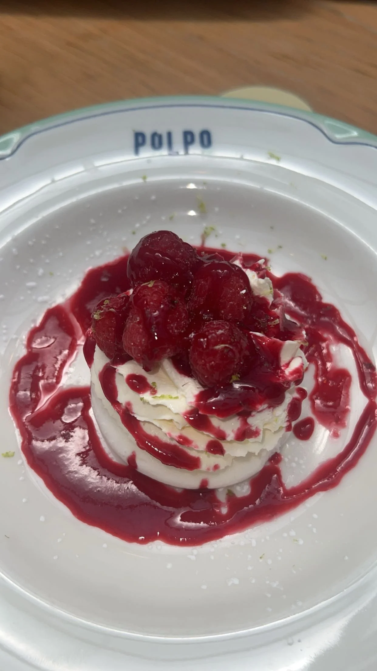 Dessert à la crème avec des fruits rouges, servi dans une assiette blanche portant l'inscription polpo