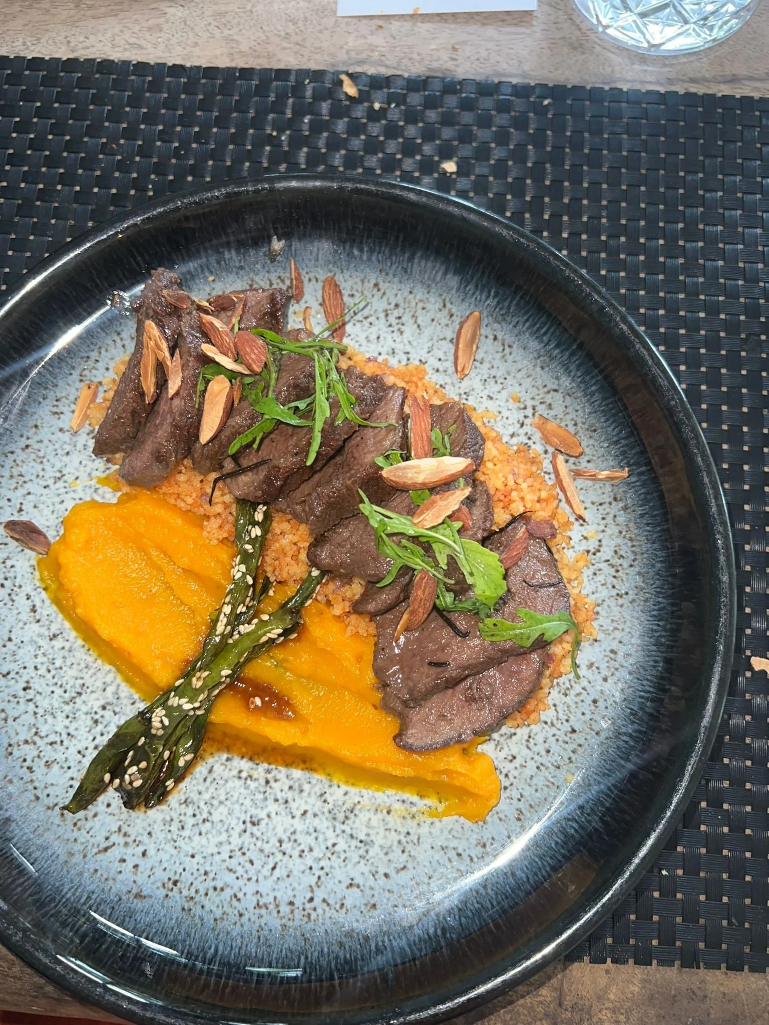 Assiette avec purée de patates douces, steak de bœuf, asperges, graines de sésame, herbes et amandes effilées.