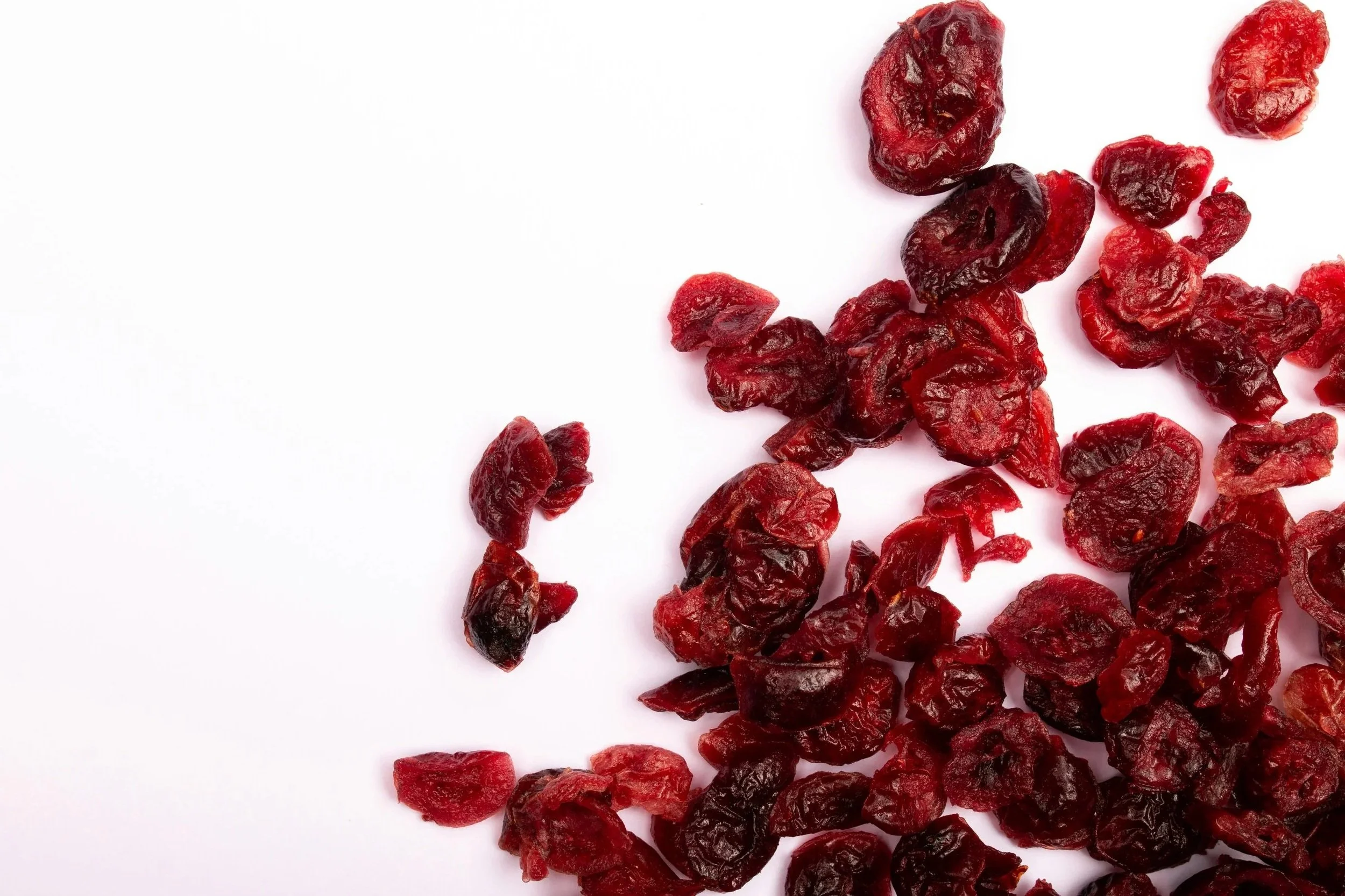 Dried cranberries scattered across a white surface.
