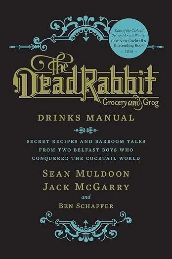 Book cover titled "The Dead Rabbit Grocery and Grog Drinks Manual" with a decorative blue design at the top and bottom. Includes a note about a cocktail award and describes secret recipes and barroom tales from Belfast boys who conquered the cocktail world. Authors are Sean Muldoon, Jack McGarry, and Ben Schaffer.