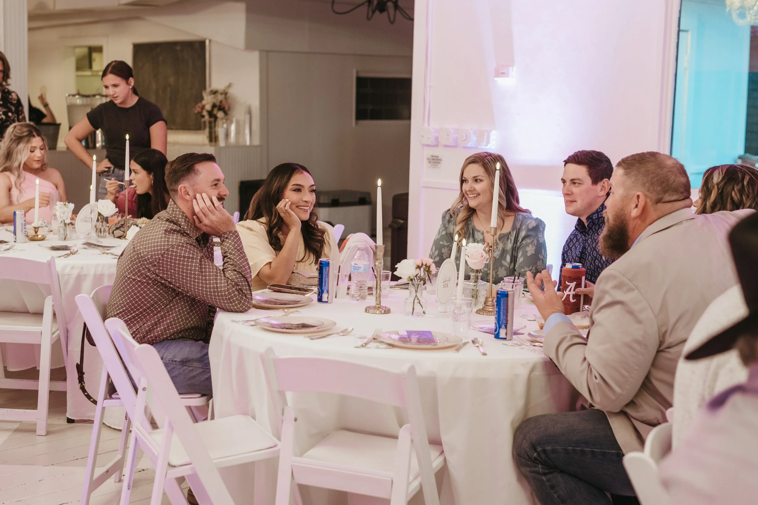 People sitting around a decorated dinner table enjoying a celebration at a party or wedding reception.