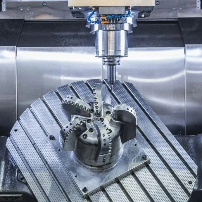 A CNC machine milling a metal component with complex curved and segmented shapes.