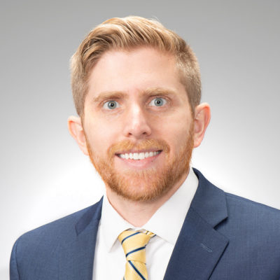 A headshot of Dr. Alex Sundermann against a gray background