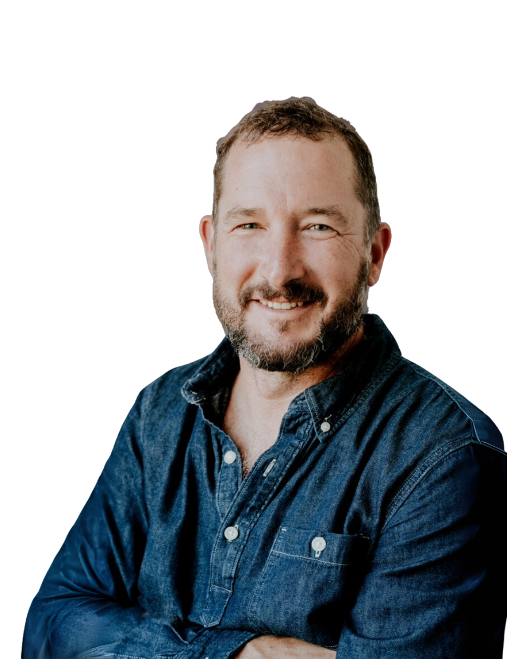 A man with a beard and short hair, smiling and wearing a dark denim shirt.