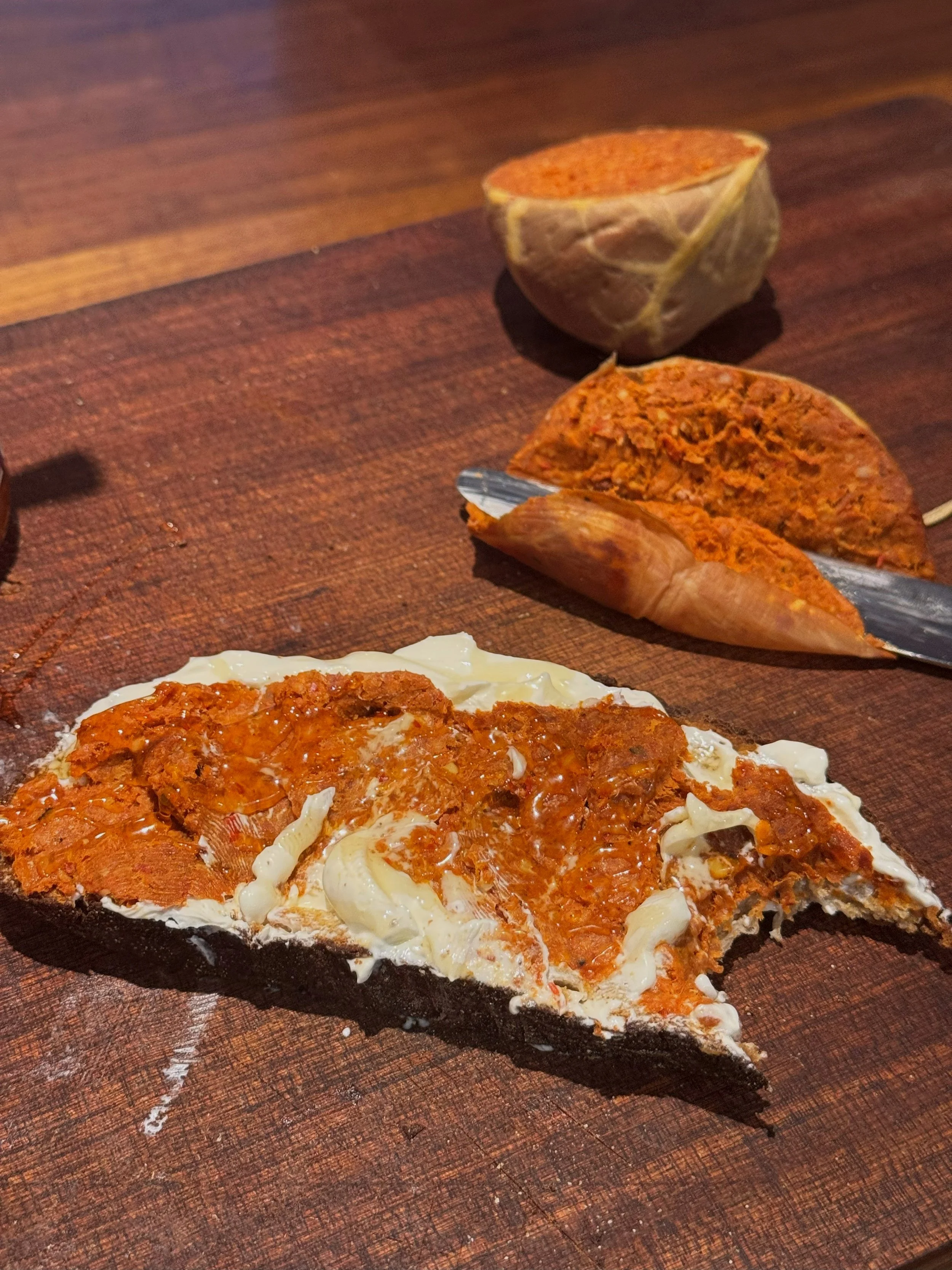 A slice of pizza with melted cheese and tomato sauce on a wooden cutting board.